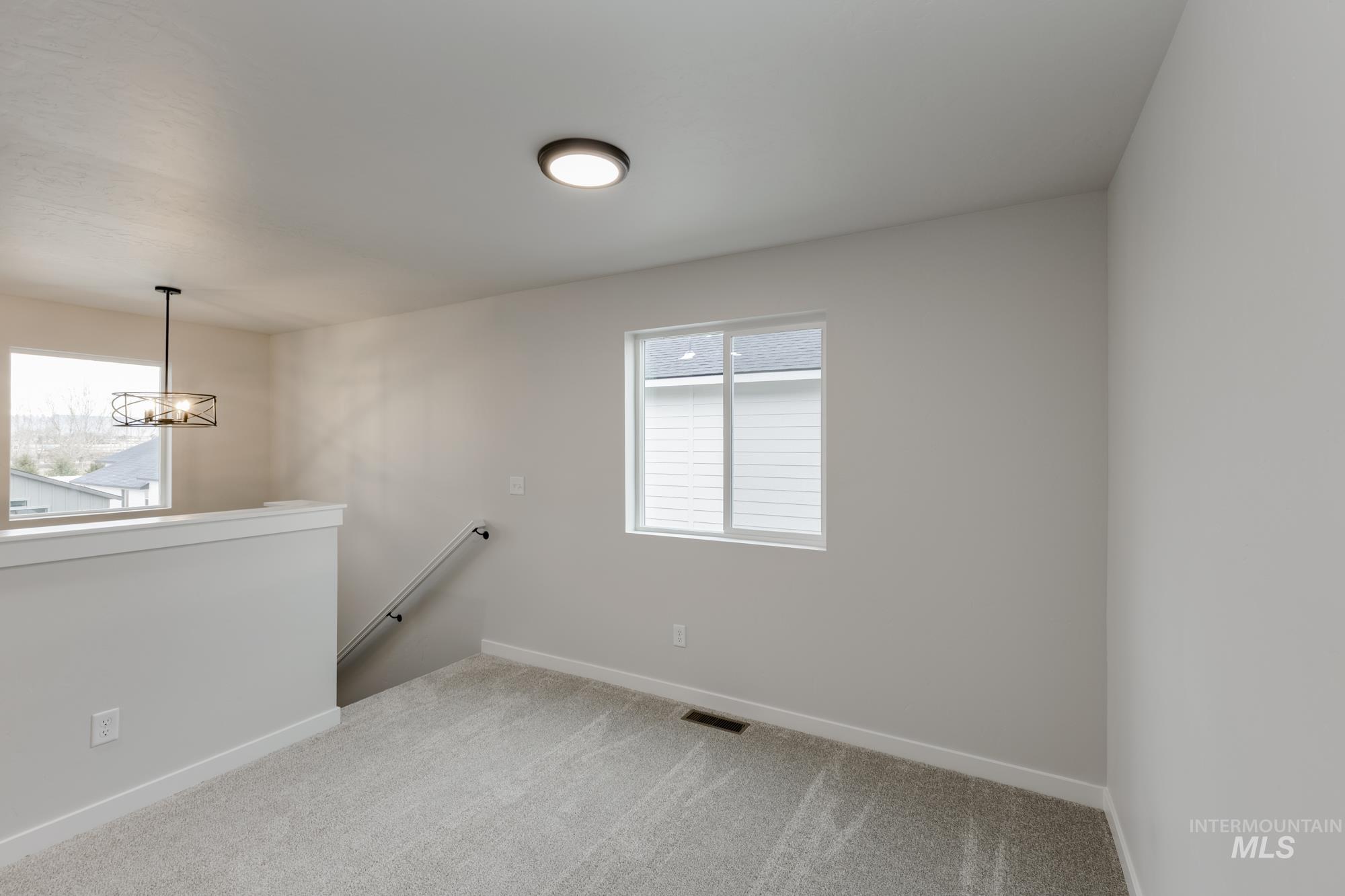 Empty room featuring light carpet and a chandelier