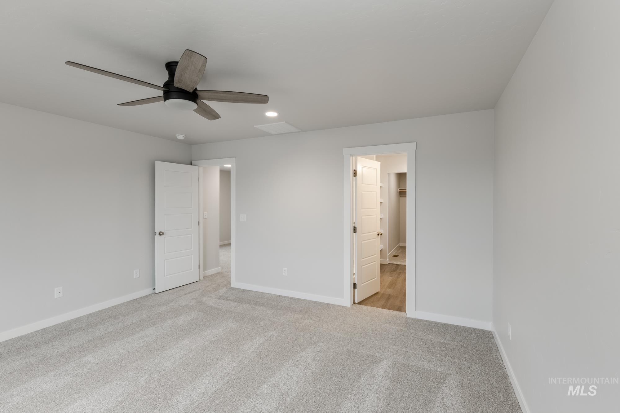 Unfurnished bedroom with light carpet, a ceiling fan, ensuite bathroom, and recessed lighting