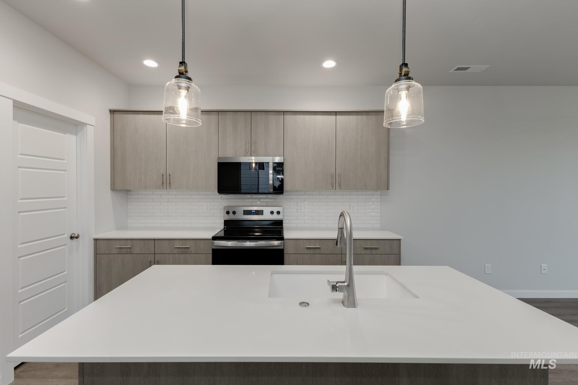 Kitchen with stainless steel appliances, modern cabinets, pendant lighting, a kitchen island with sink, and backsplash