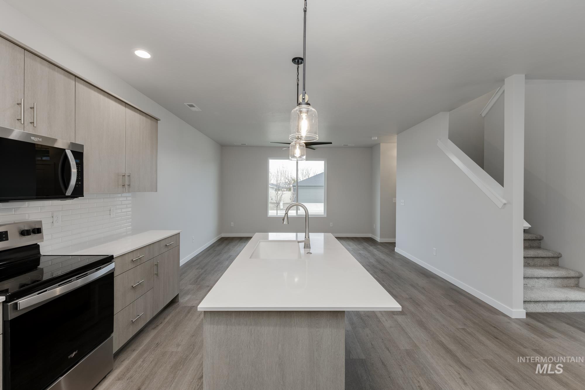 Kitchen featuring appliances with stainless steel finishes, modern cabinets, hanging light fixtures, light brown cabinets, and recessed lighting