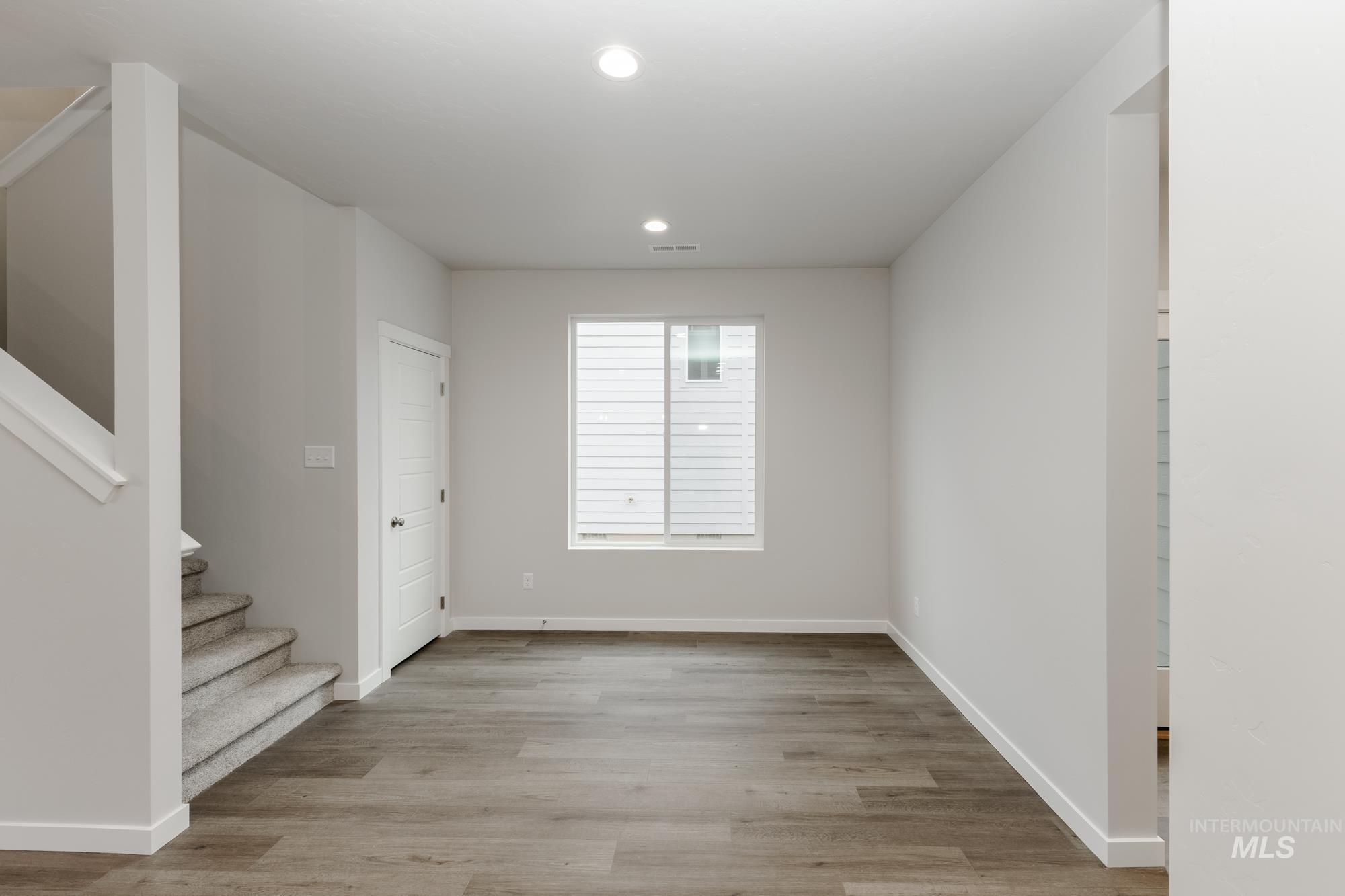 Unfurnished room with stairs, light wood-type flooring, and recessed lighting
