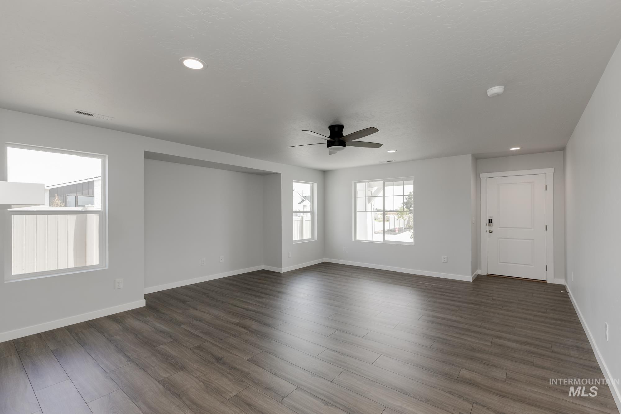 Empty room featuring a ceiling fan, recessed lighting, and dark wood-style floors
