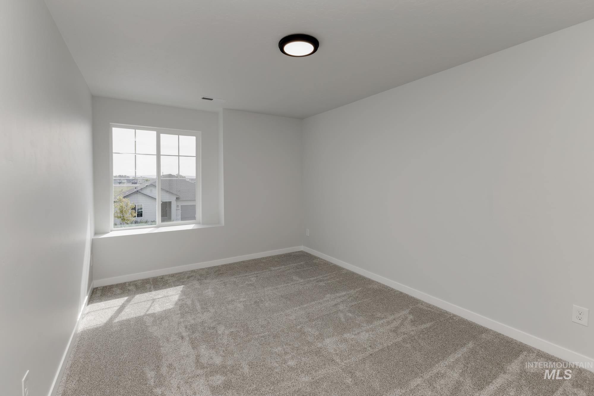 Spare room featuring light carpet and baseboards