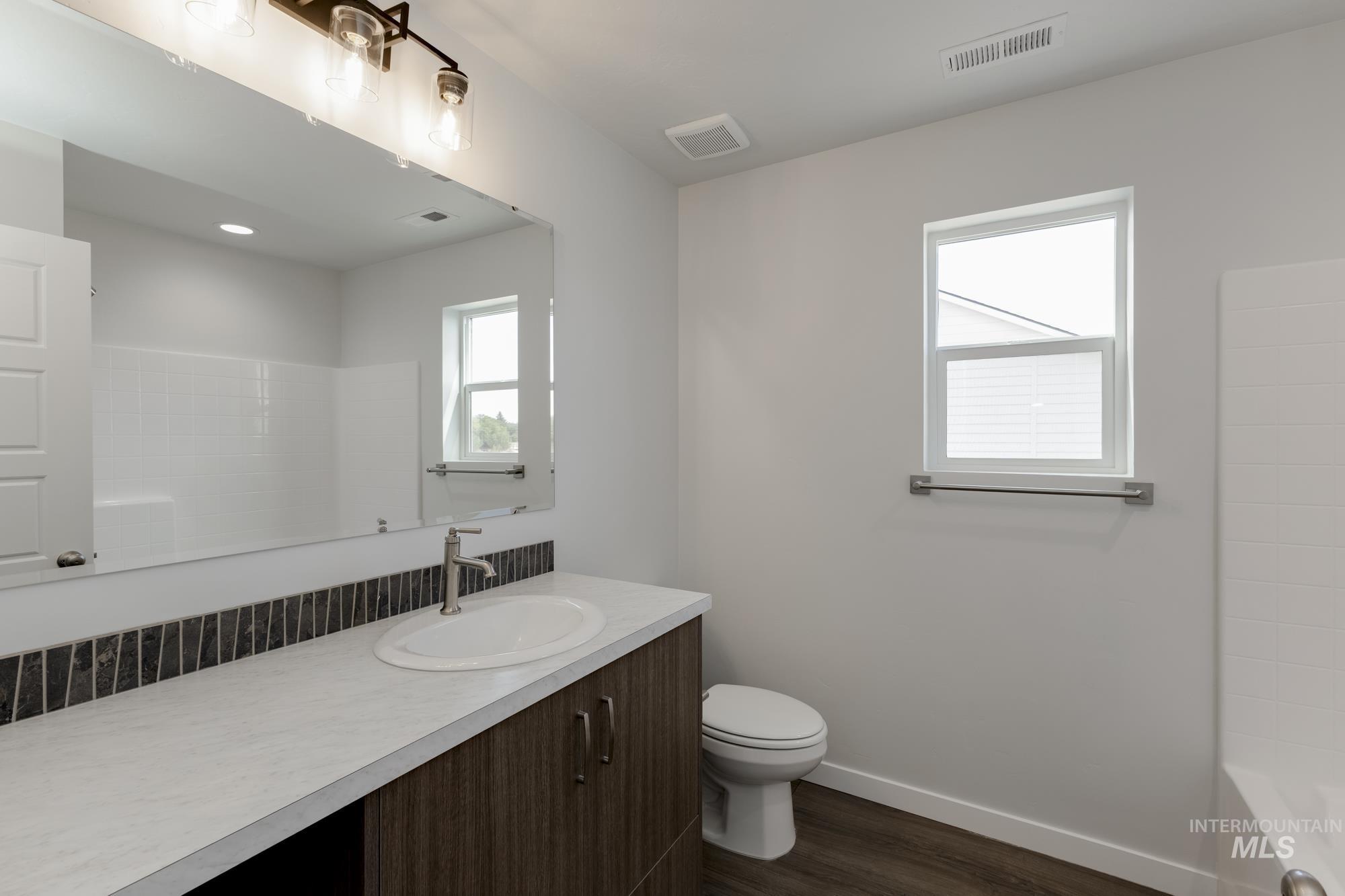 Full bath featuring vanity, dark wood-style floors, and washtub / shower combination
