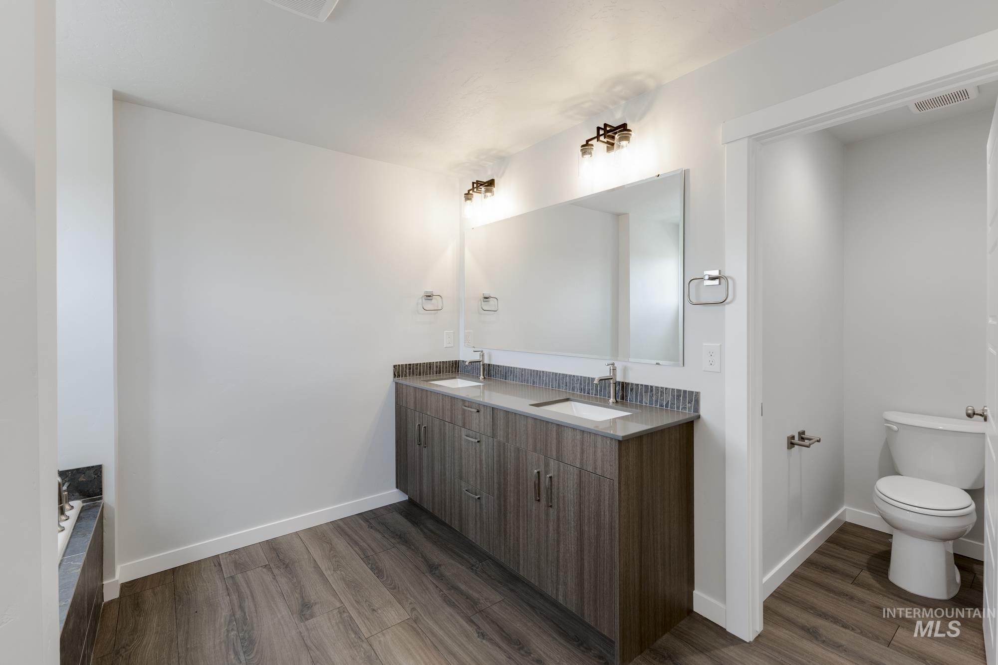 Full bath featuring dark wood-style floors and double vanity