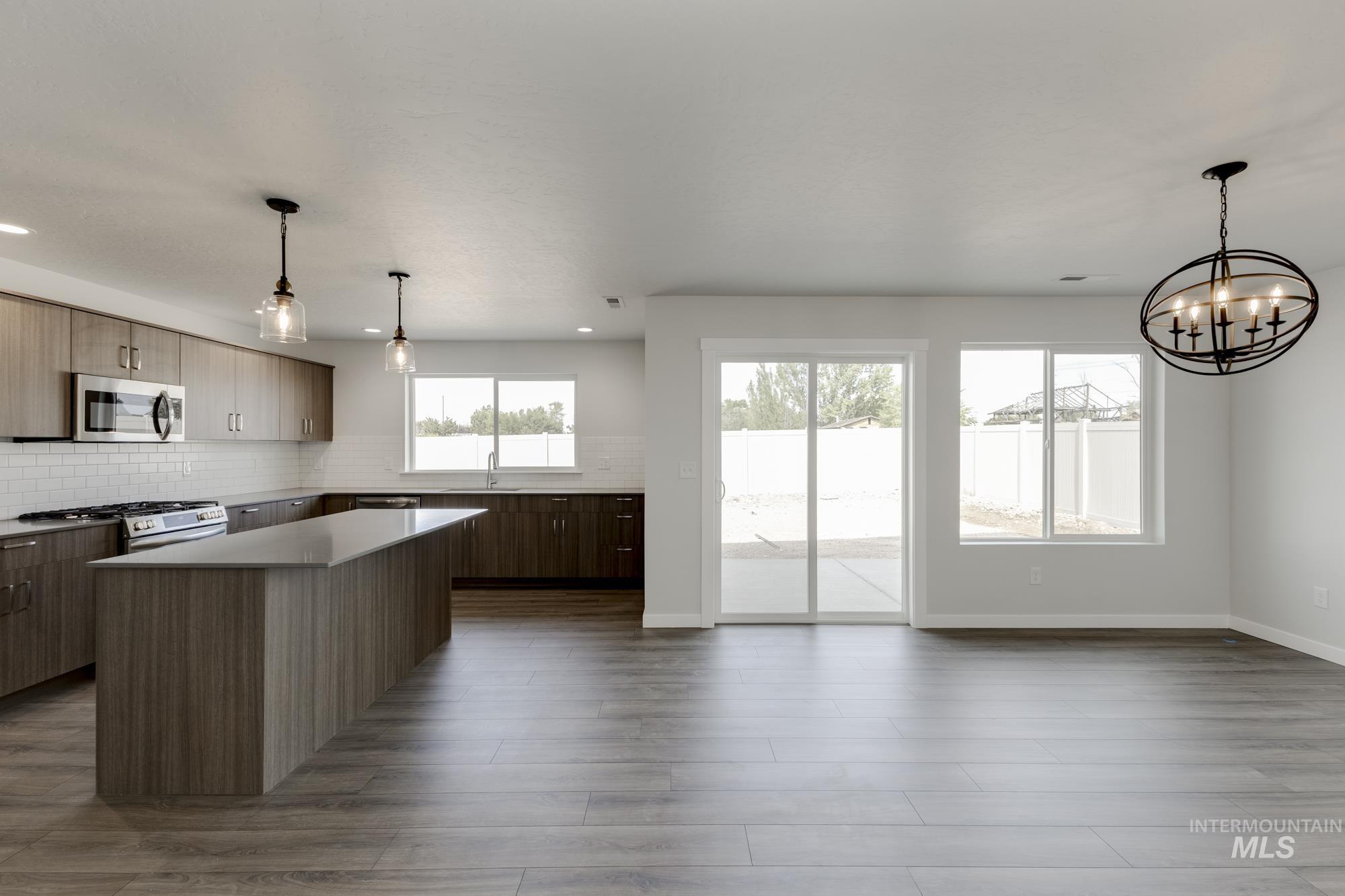 Kitchen featuring hanging light fixtures, decorative backsplash, a center island, and appliances with stainless steel finishes