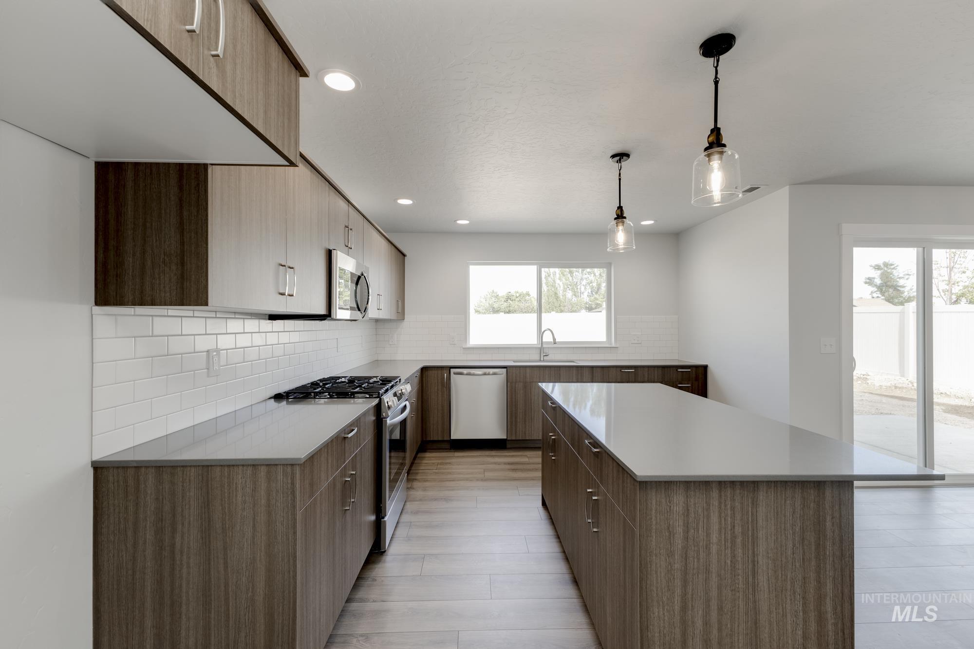 Kitchen featuring stainless steel appliances, modern cabinets, decorative backsplash, a center island, and pendant lighting