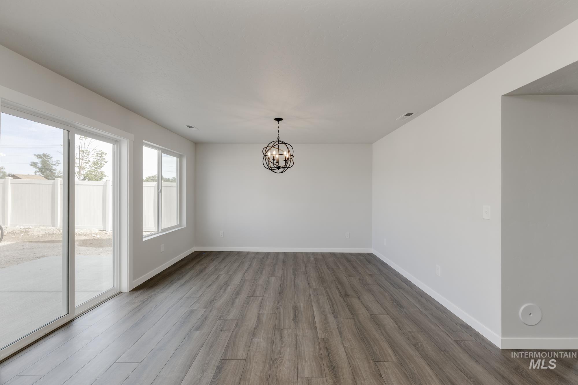 Unfurnished dining area with dark wood-style floors and a chandelier