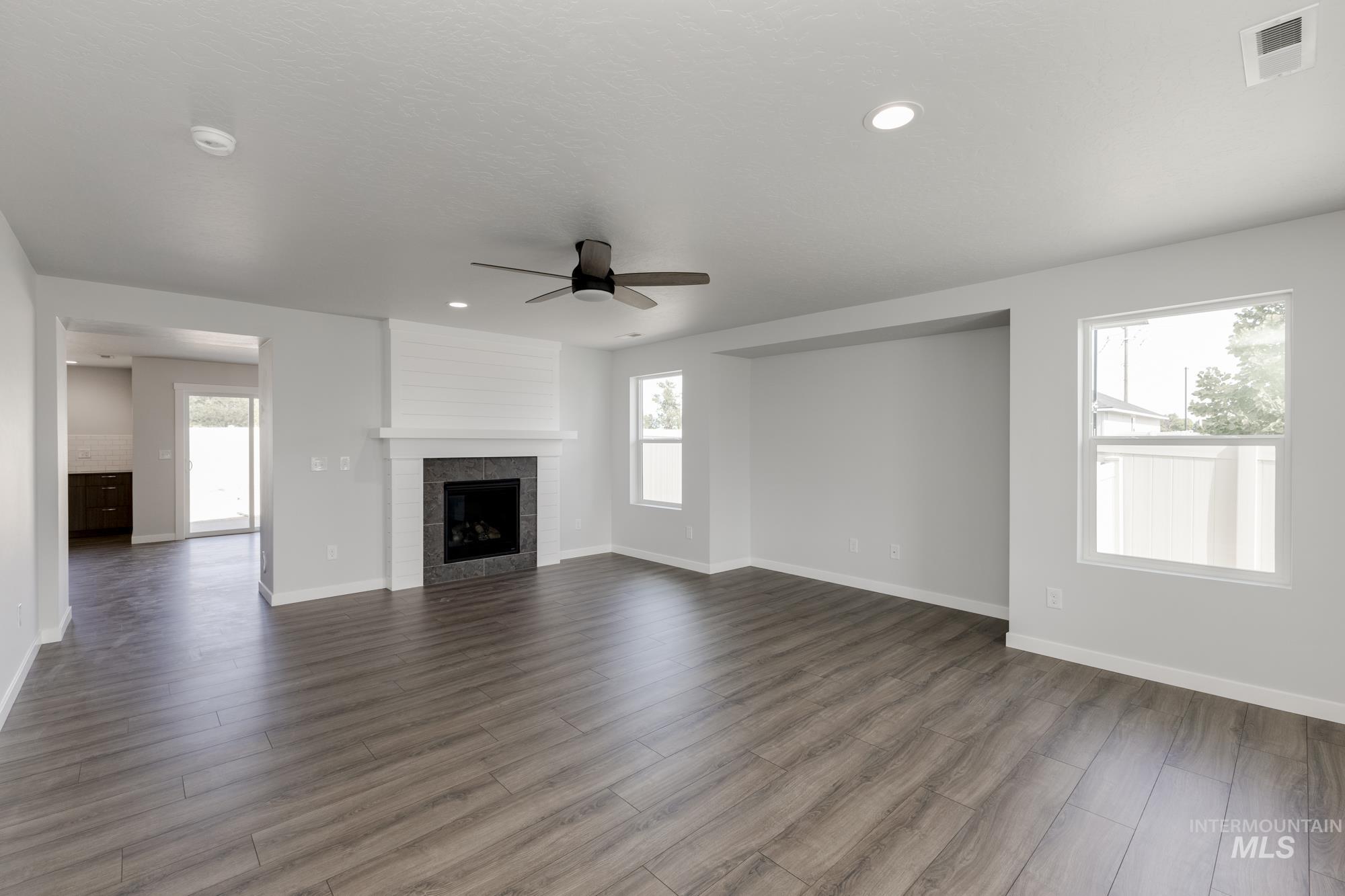 Unfurnished living room featuring wood finished floors, ceiling fan, a fireplace, and recessed lighting