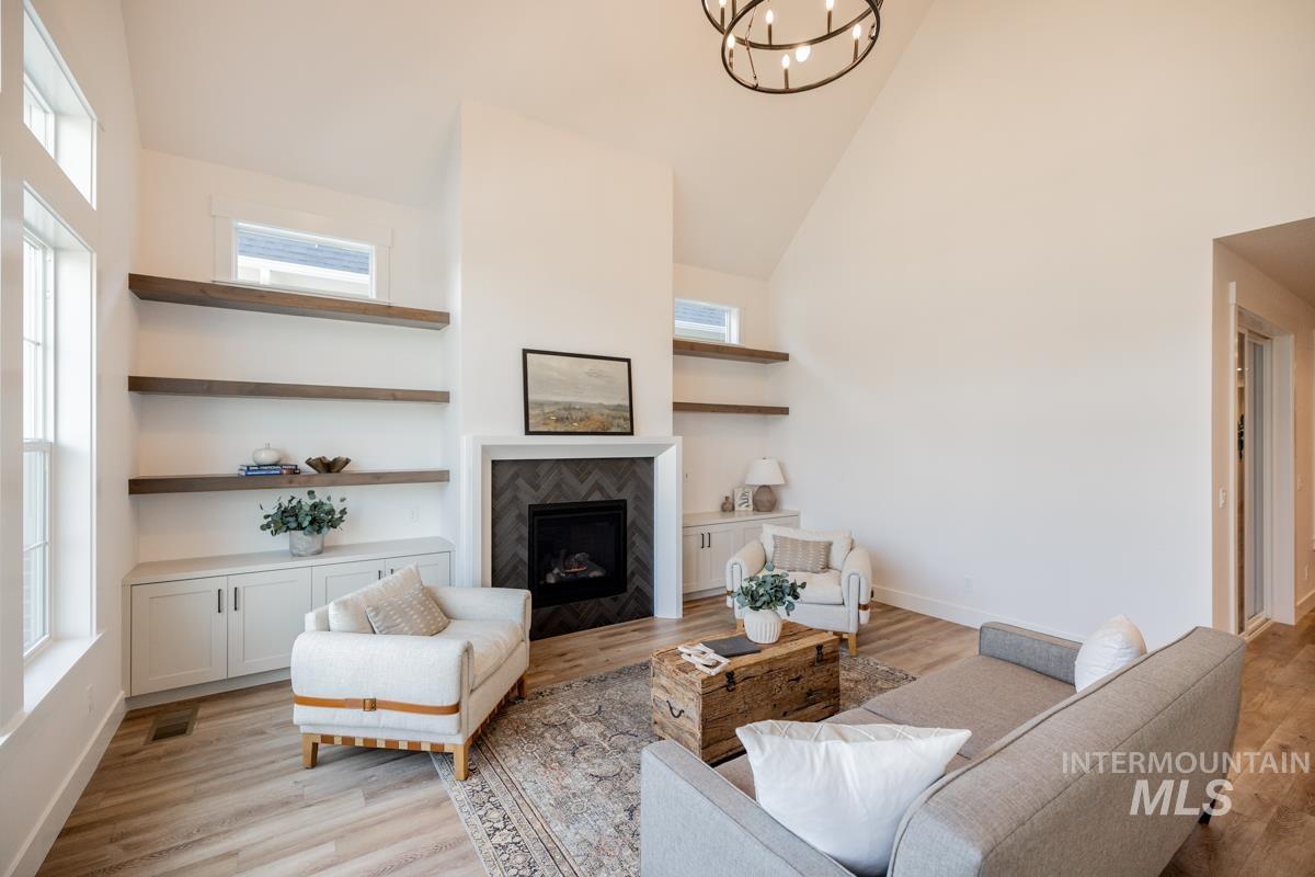 Living room featuring high vaulted ceiling, a tiled fireplace, and light wood-style floors