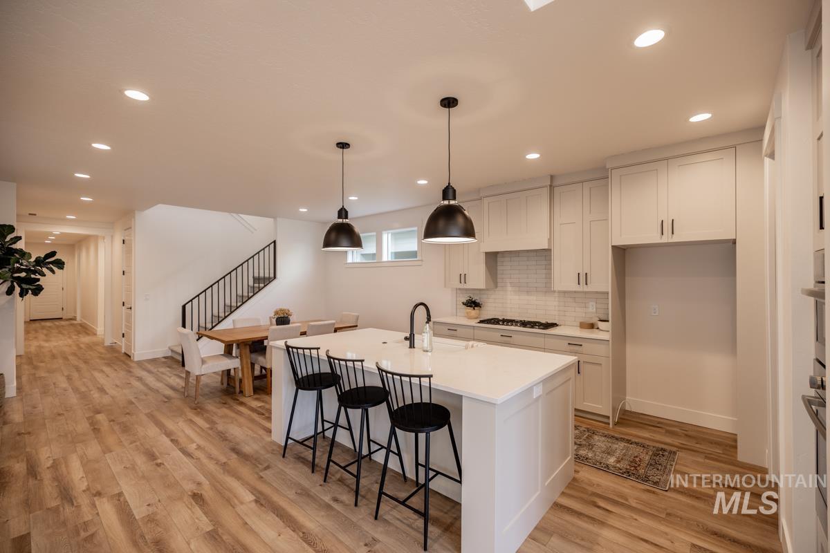 Kitchen featuring decorative backsplash, a breakfast bar, pendant lighting, light wood-style floors, and recessed lighting