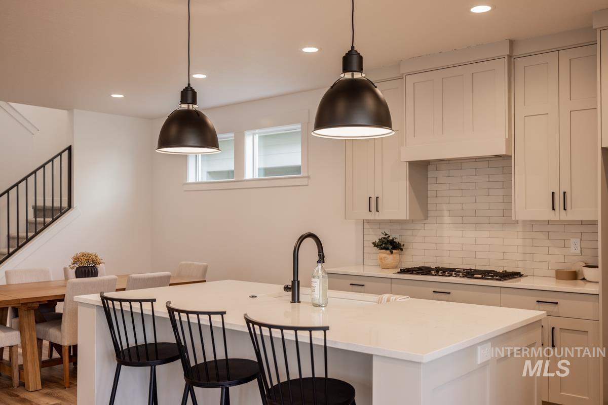 Kitchen featuring recessed lighting, a breakfast bar, hanging light fixtures, decorative backsplash, and a center island with sink