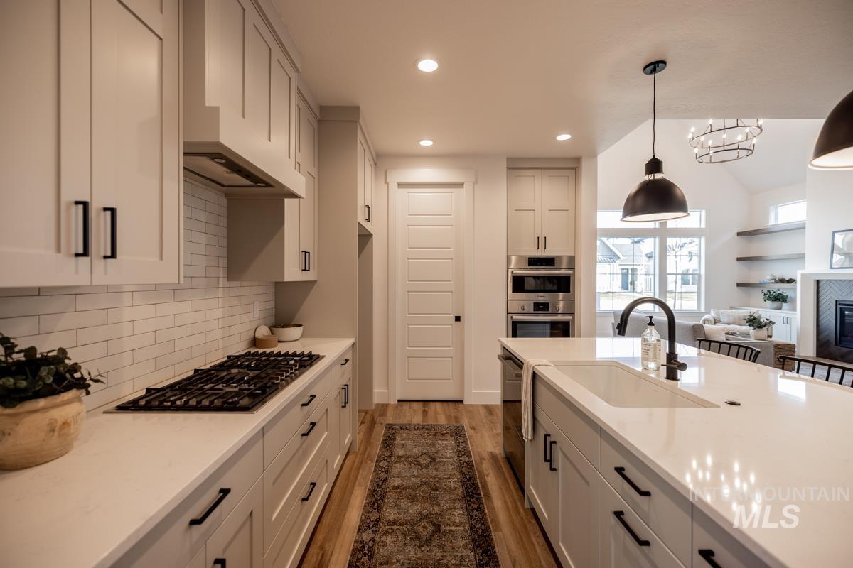 Kitchen featuring light wood-style floors, light stone counters, recessed lighting, pendant lighting, and custom range hood