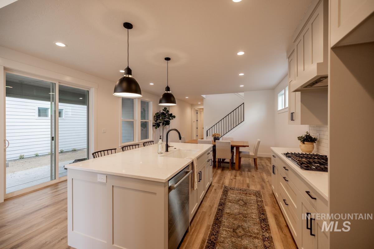 Kitchen with hanging light fixtures, white cabinets, appliances with stainless steel finishes, light wood-style floors, and recessed lighting