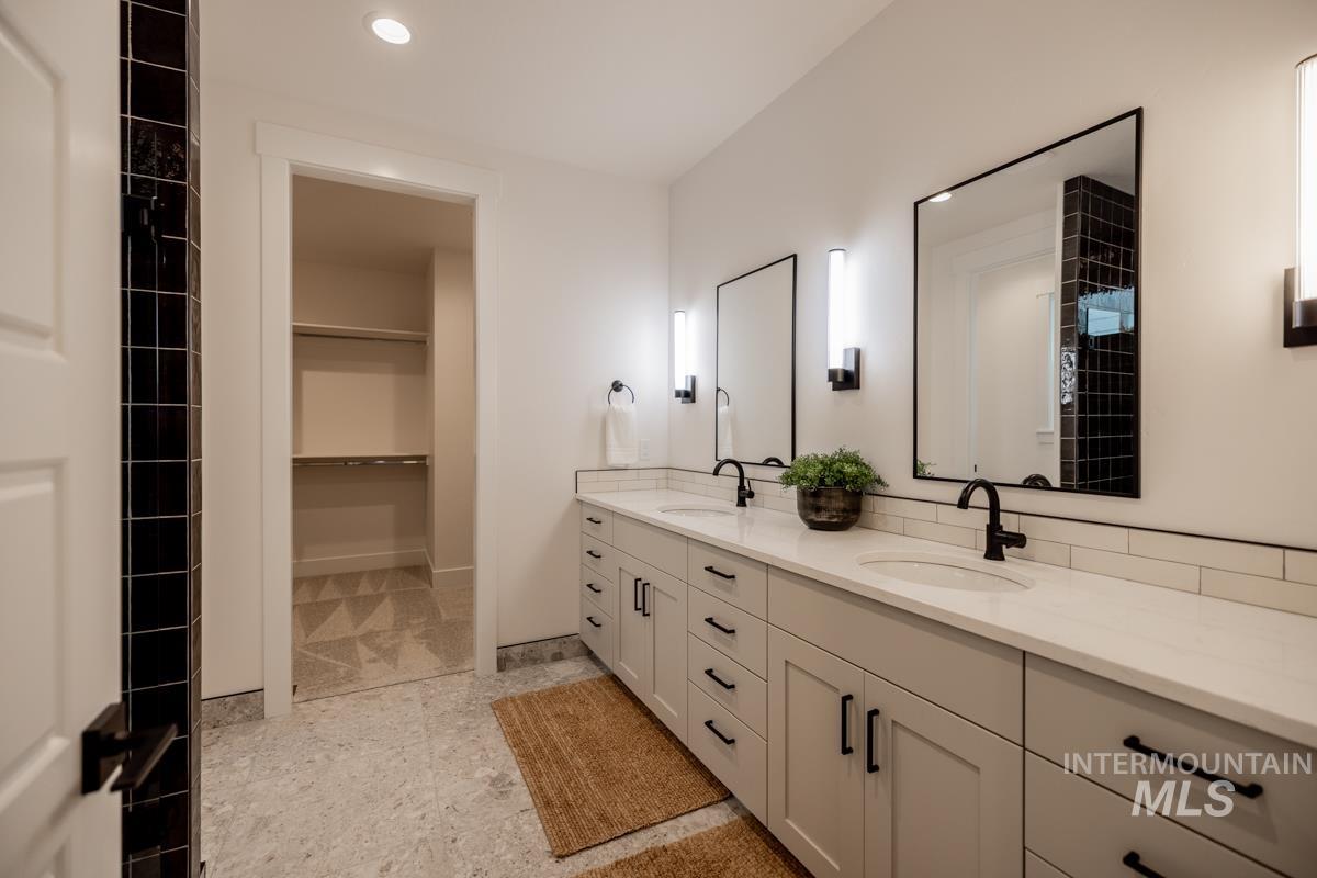 Bathroom with double vanity, a spacious closet, and recessed lighting