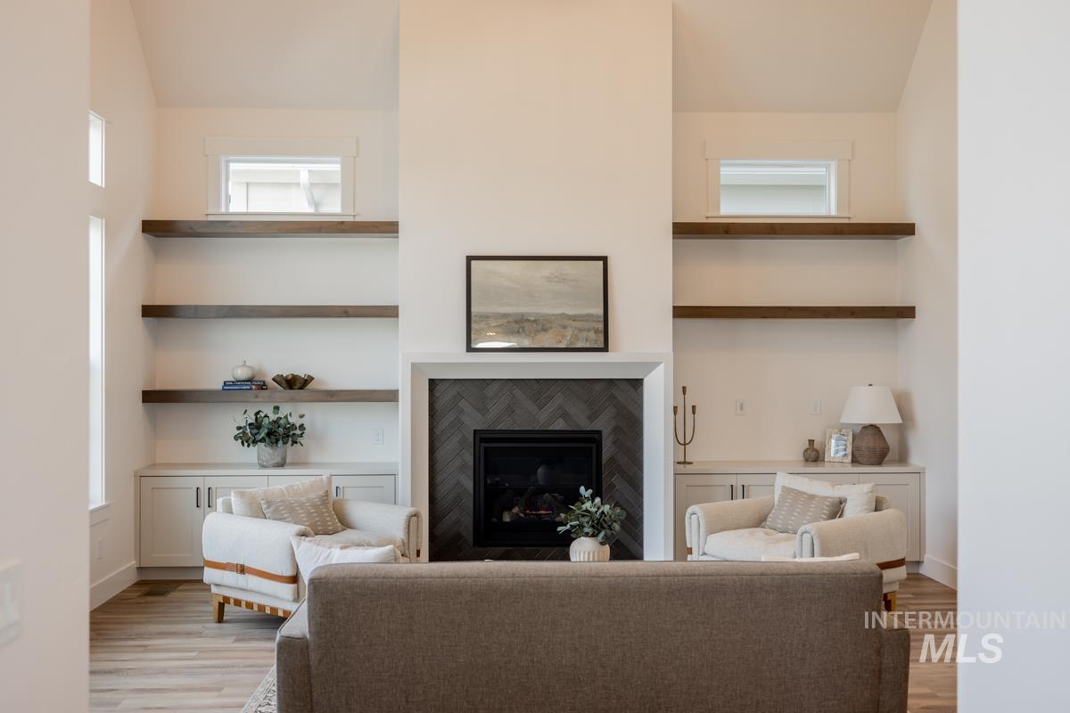 Living room with a glass covered fireplace, light wood finished floors, and a high ceiling