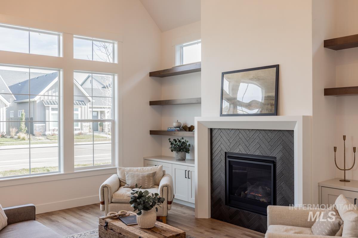 Living area featuring light wood-type flooring, a glass covered fireplace, and vaulted ceiling