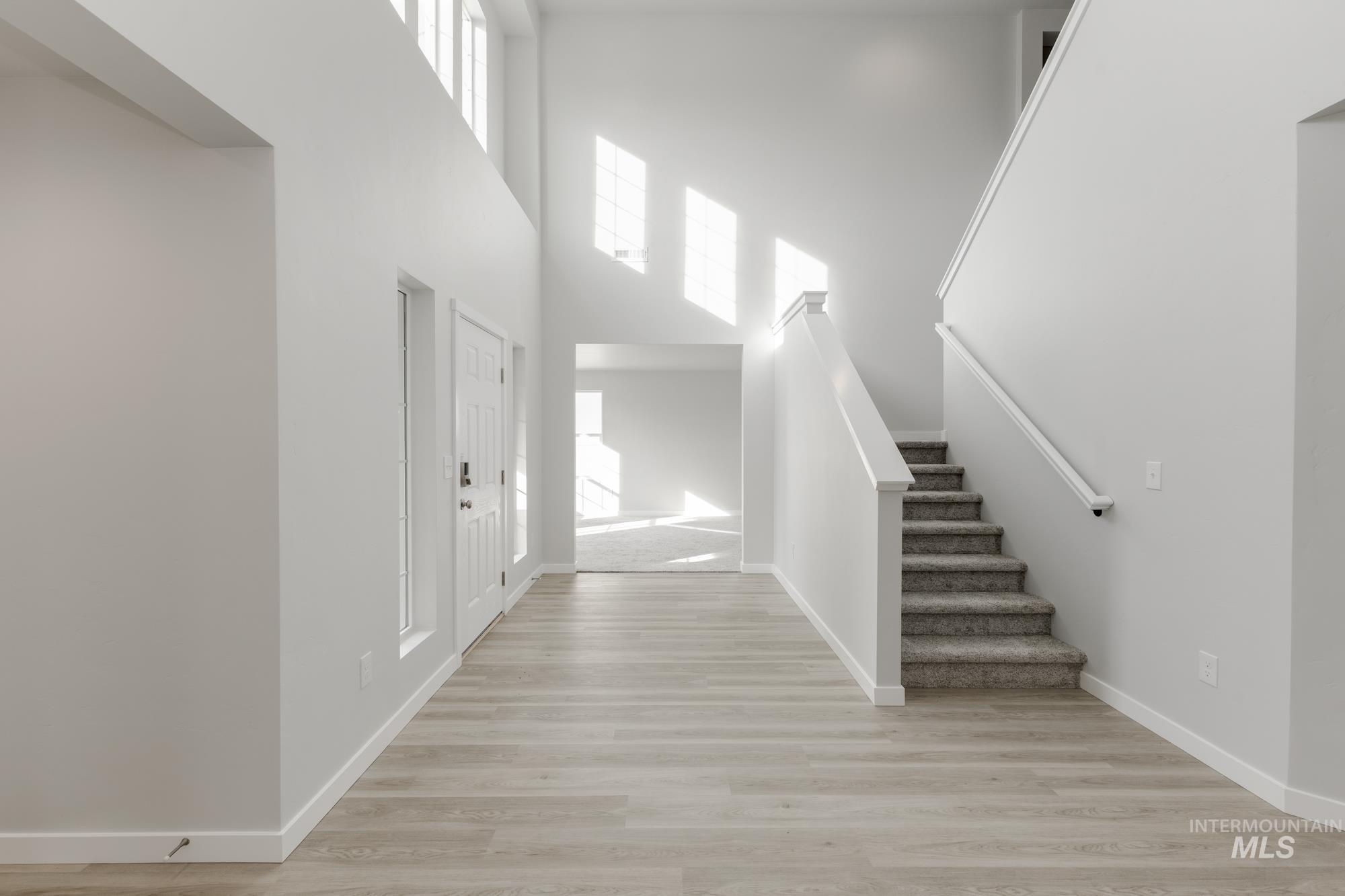 Foyer with stairs, light wood-type flooring, and a high ceiling