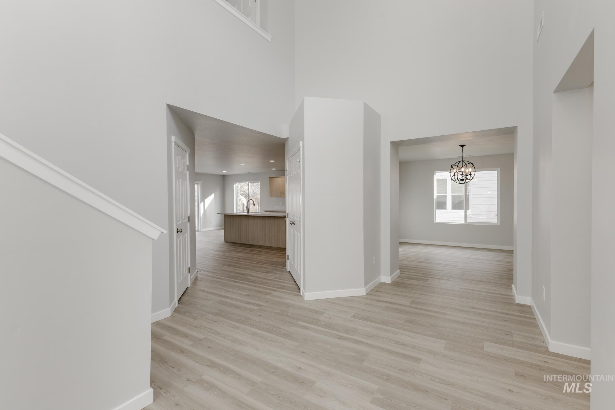 Hallway with a chandelier, light wood-style floors, and a towering ceiling