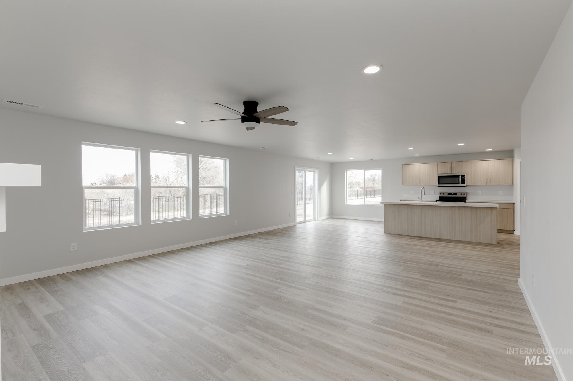 Unfurnished living room with light wood-style floors, ceiling fan, and recessed lighting