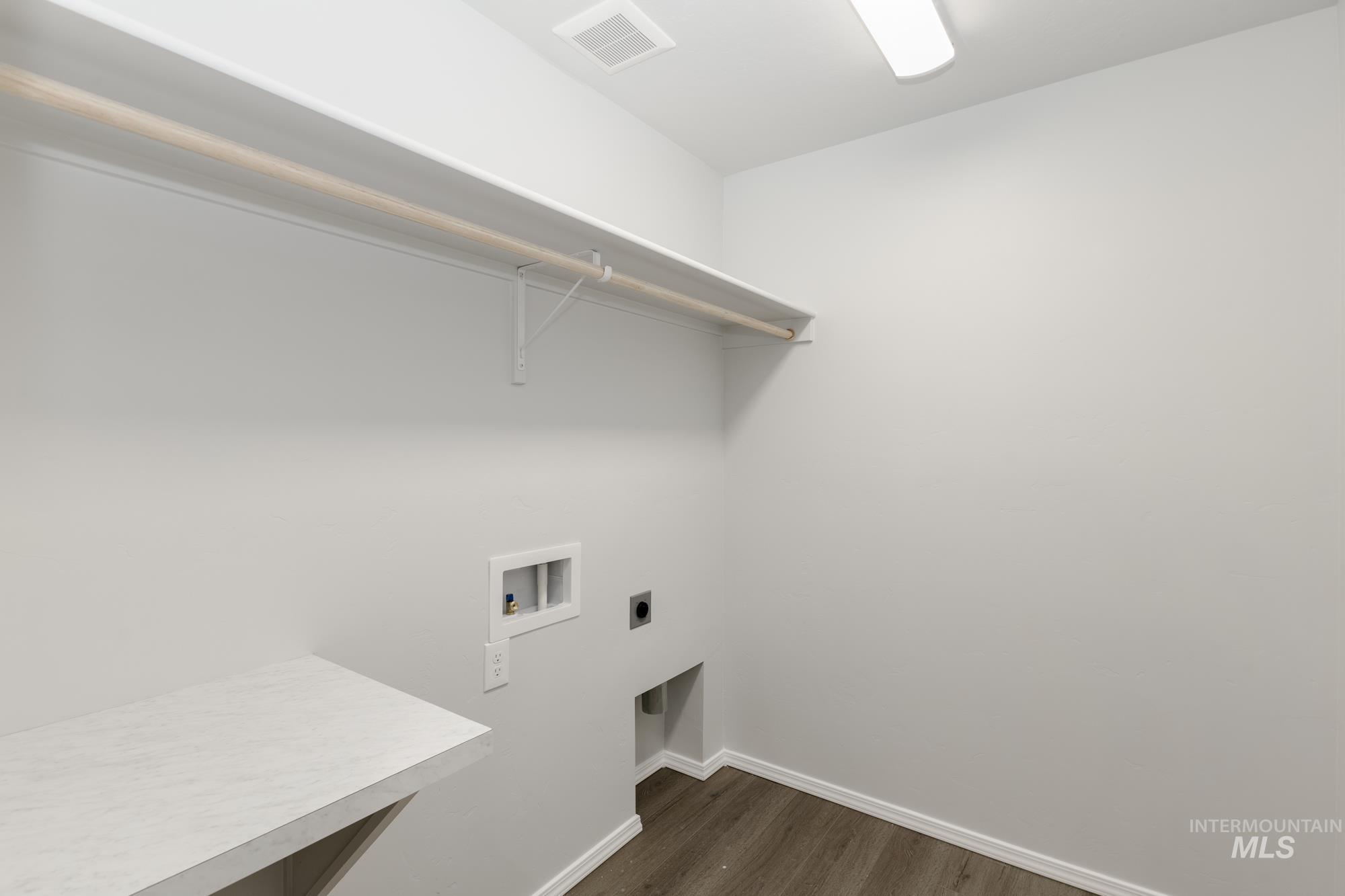 Washroom featuring dark wood-style flooring, hookup for a washing machine, and hookup for an electric dryer