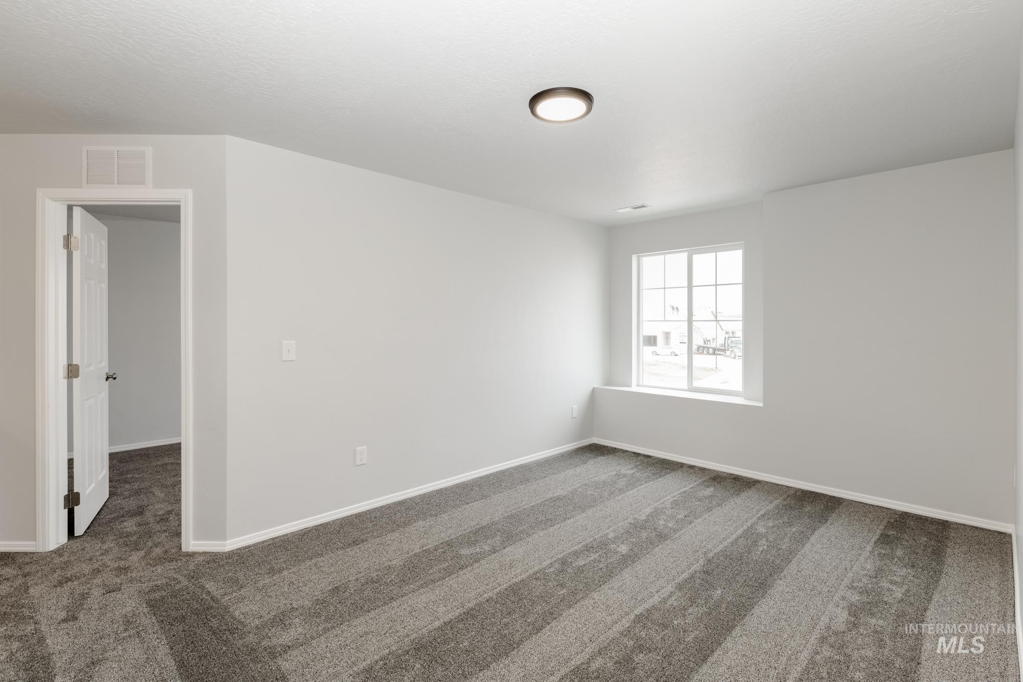 Spare room featuring dark carpet and baseboards