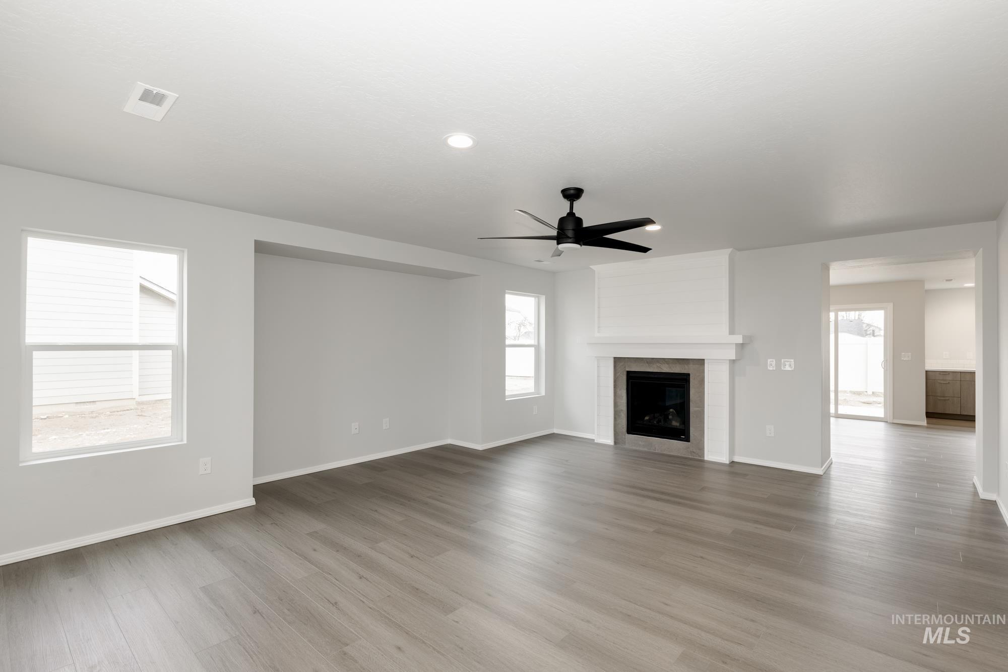 Unfurnished living room featuring a ceiling fan, a fireplace, light wood finished floors, and recessed lighting