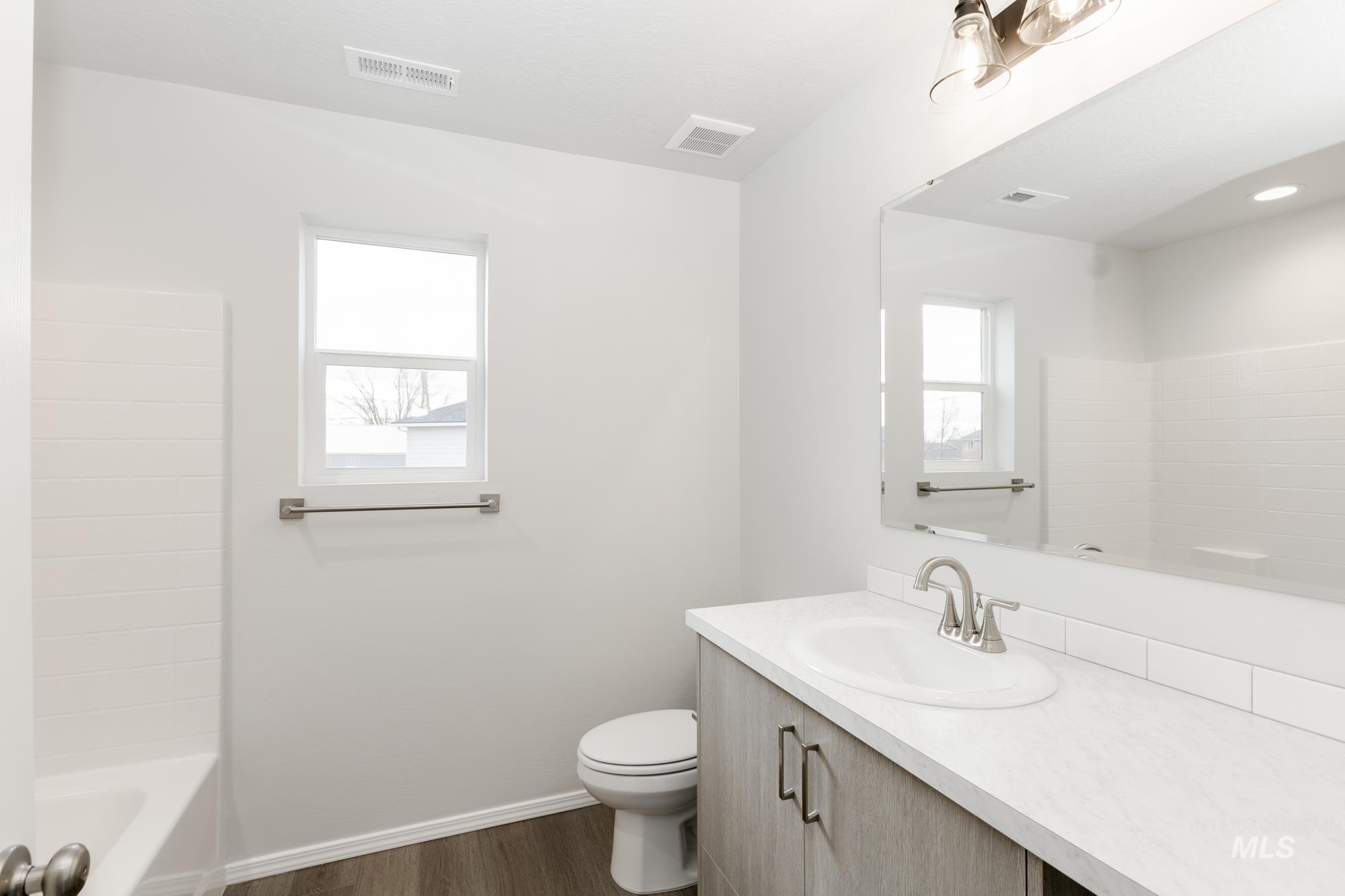 Full bathroom with vanity, dark wood-style flooring, and washtub / shower combination