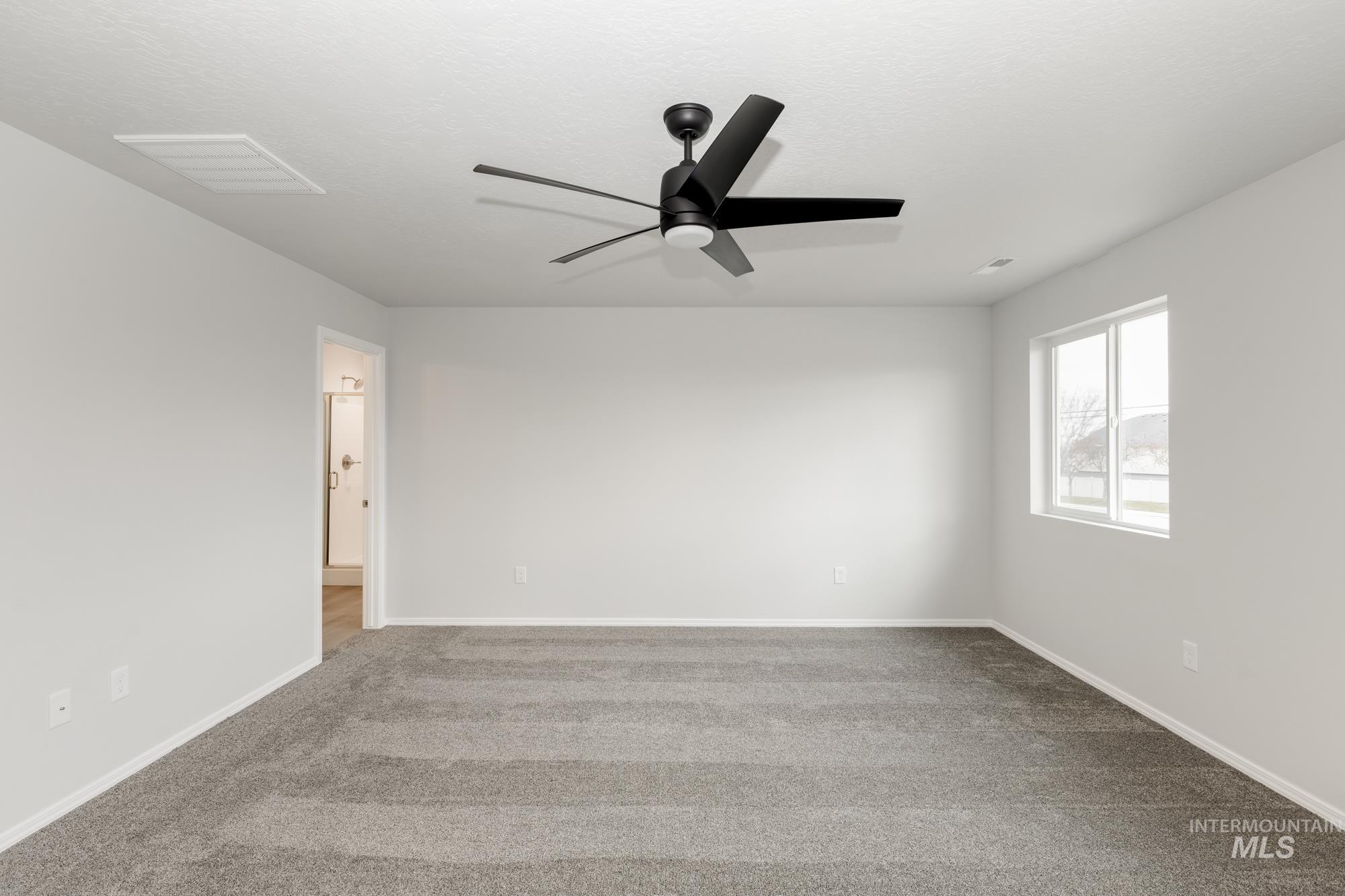 Spare room featuring light carpet and a ceiling fan