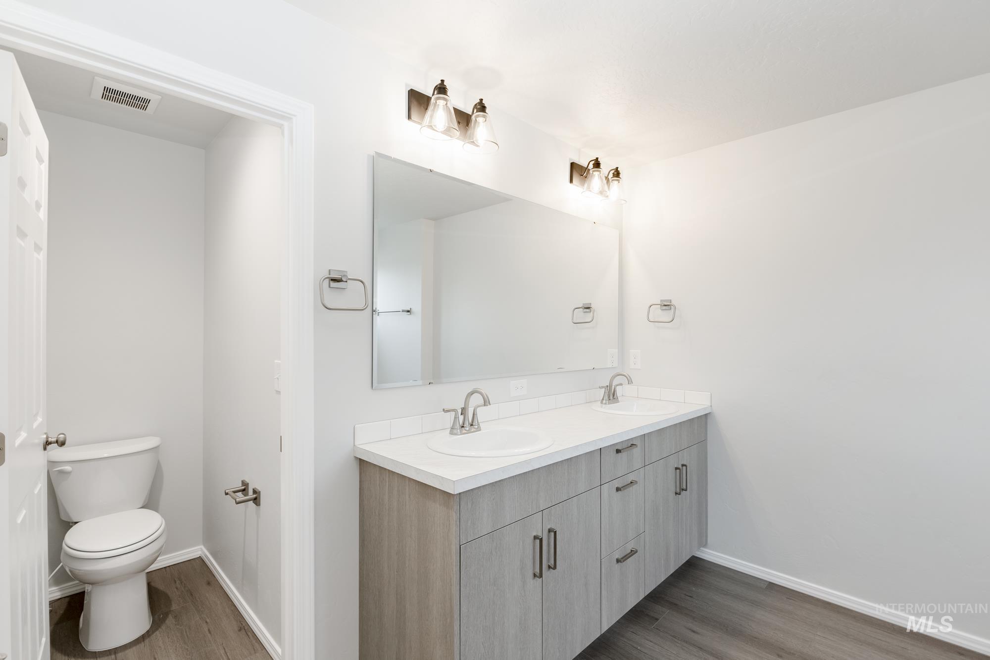 Bathroom with double vanity and dark wood-style flooring