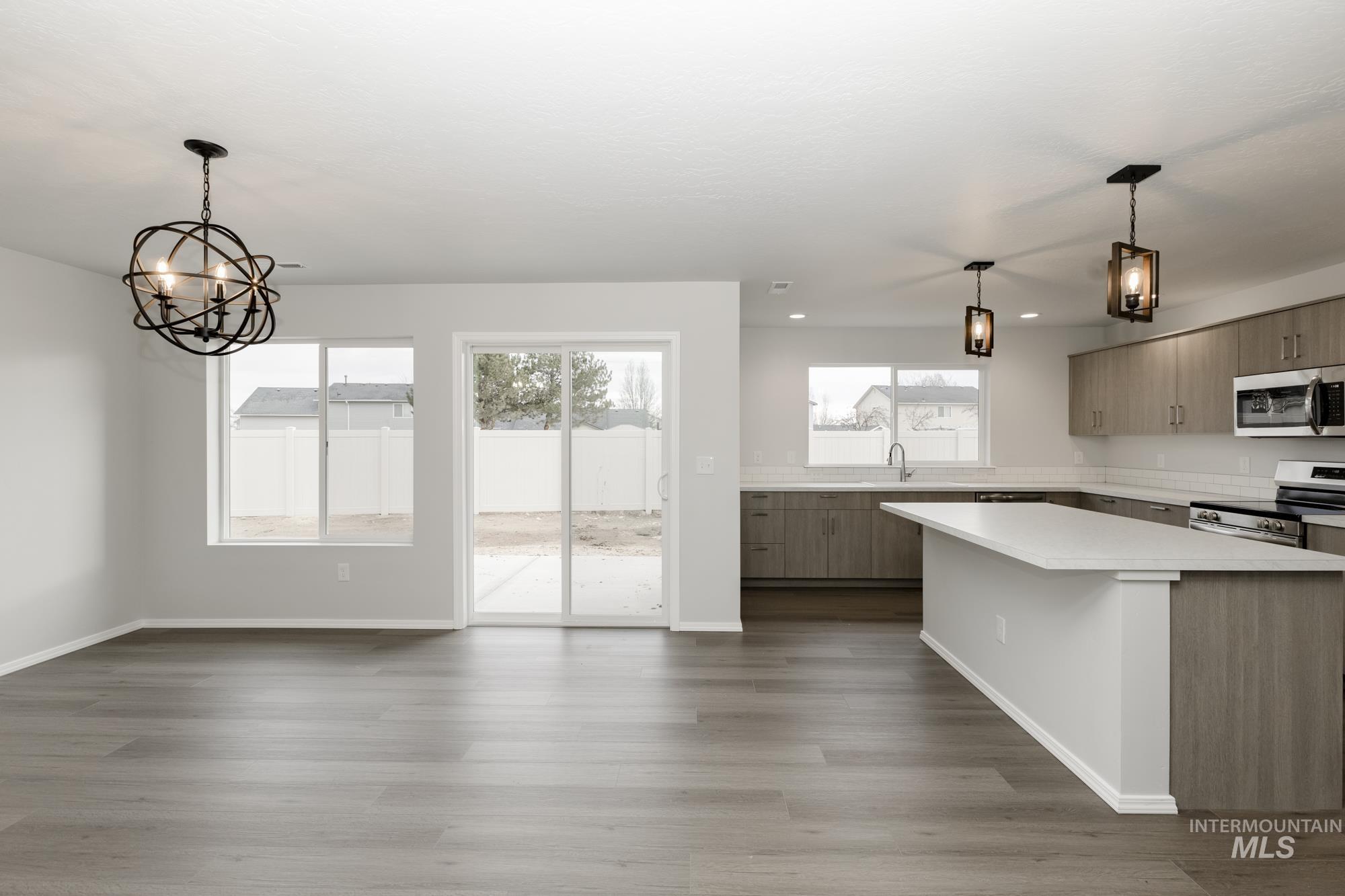 Kitchen with hanging light fixtures, appliances with stainless steel finishes, a chandelier, and modern cabinets