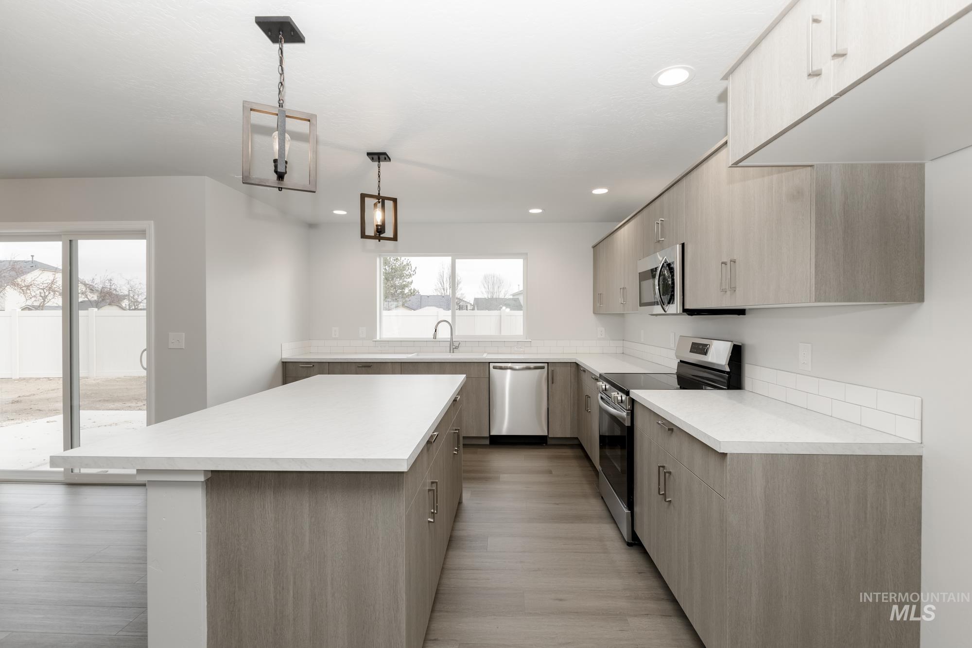 Kitchen with appliances with stainless steel finishes, light countertops, a kitchen island, modern cabinets, and recessed lighting