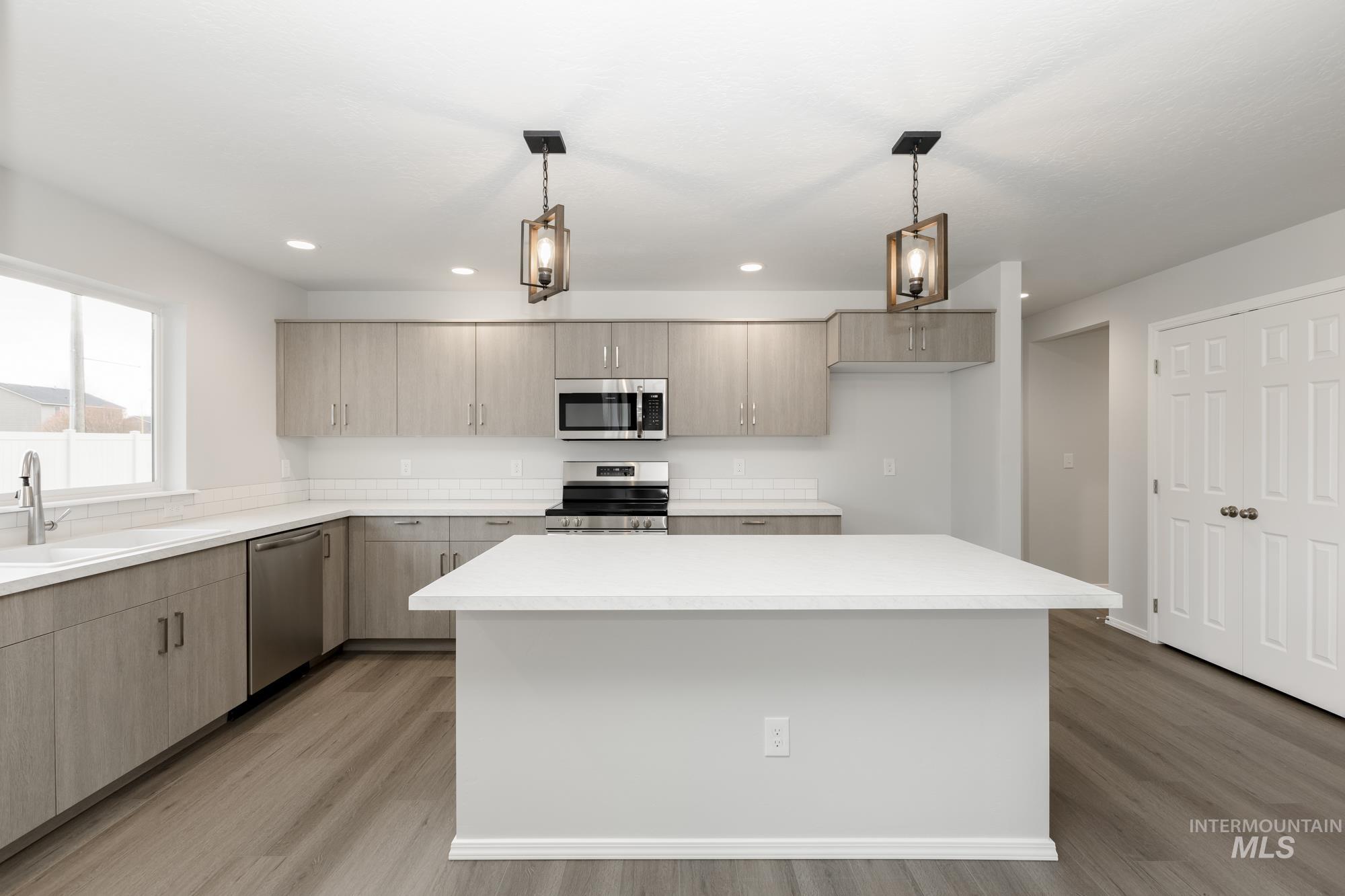 Kitchen with stainless steel appliances, decorative light fixtures, light wood-style floors, modern cabinets, and recessed lighting