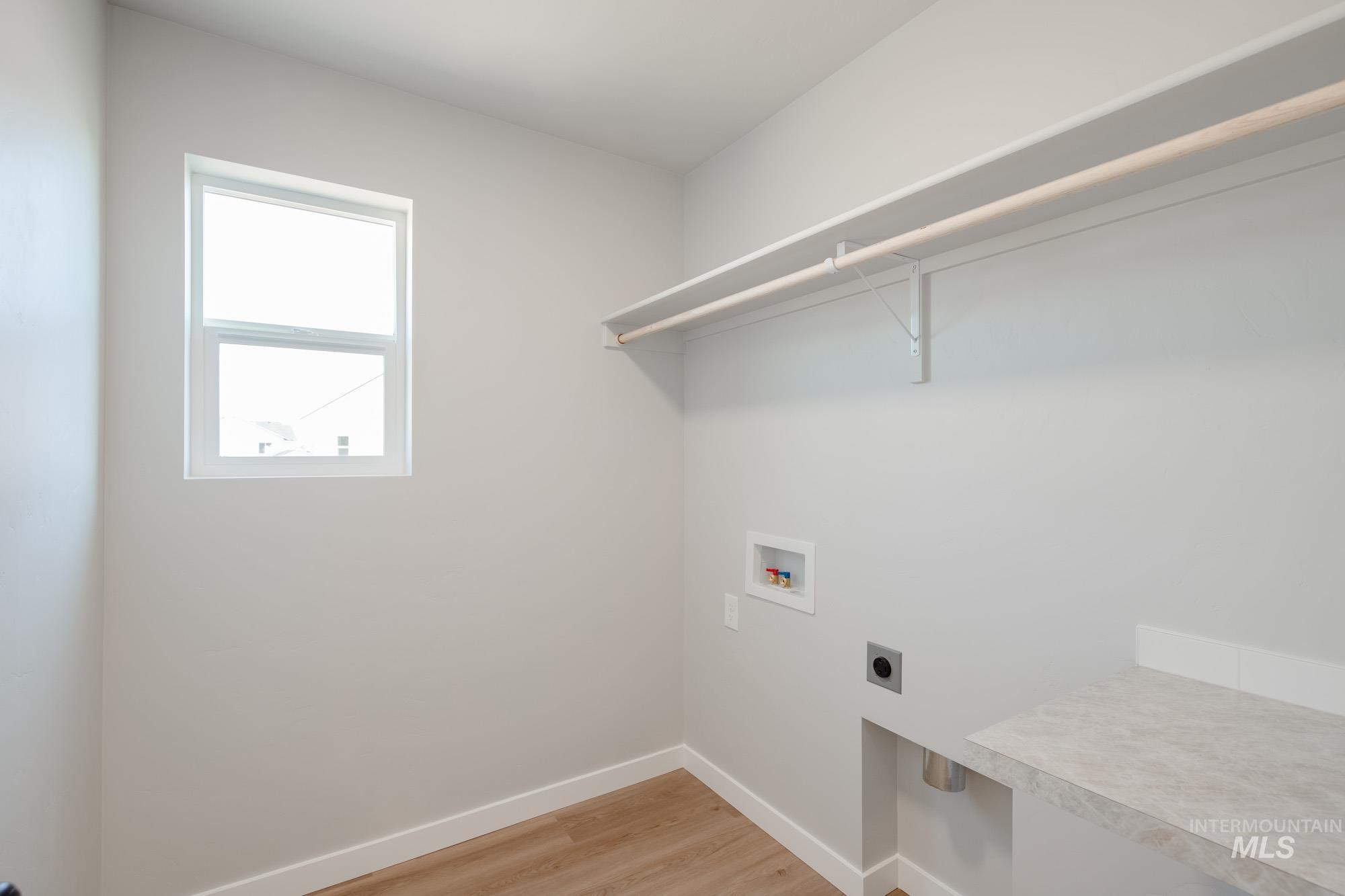 Washroom with light wood-style floors, hookup for a washing machine, and electric dryer hookup