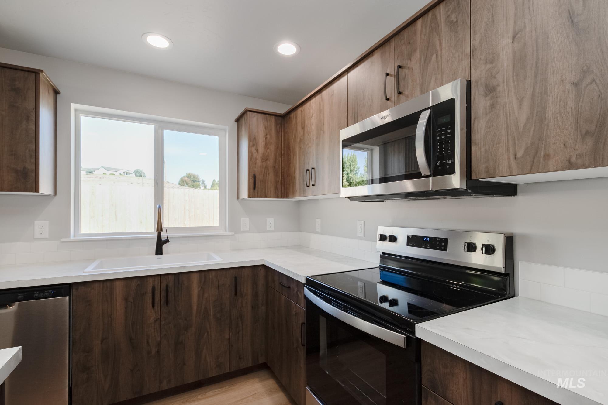 Kitchen featuring stainless steel appliances, light countertops, light wood finished floors, healthy amount of natural light, and recessed lighting