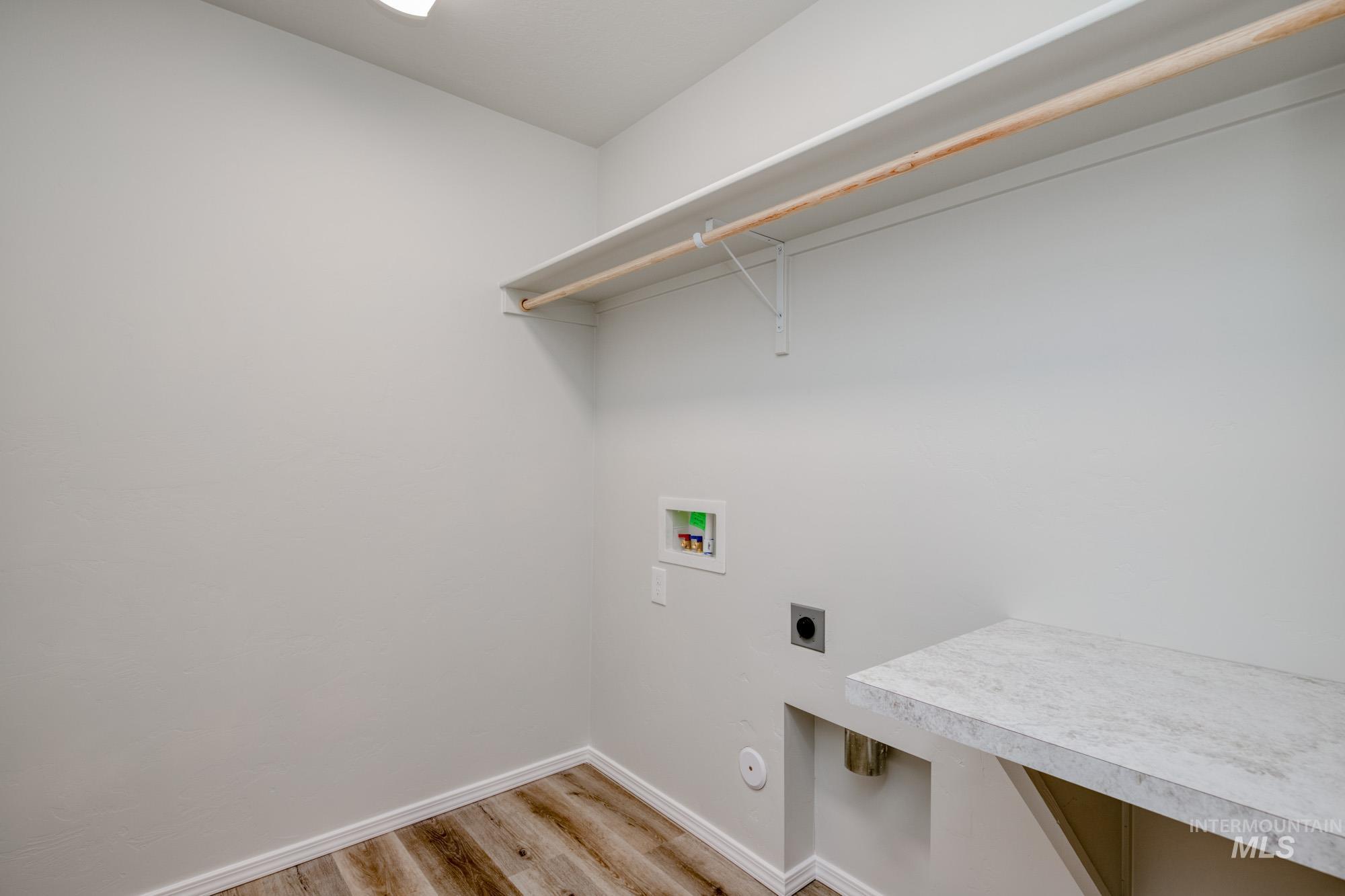 Laundry room with hookup for an electric dryer, light wood finished floors, and hookup for a washing machine