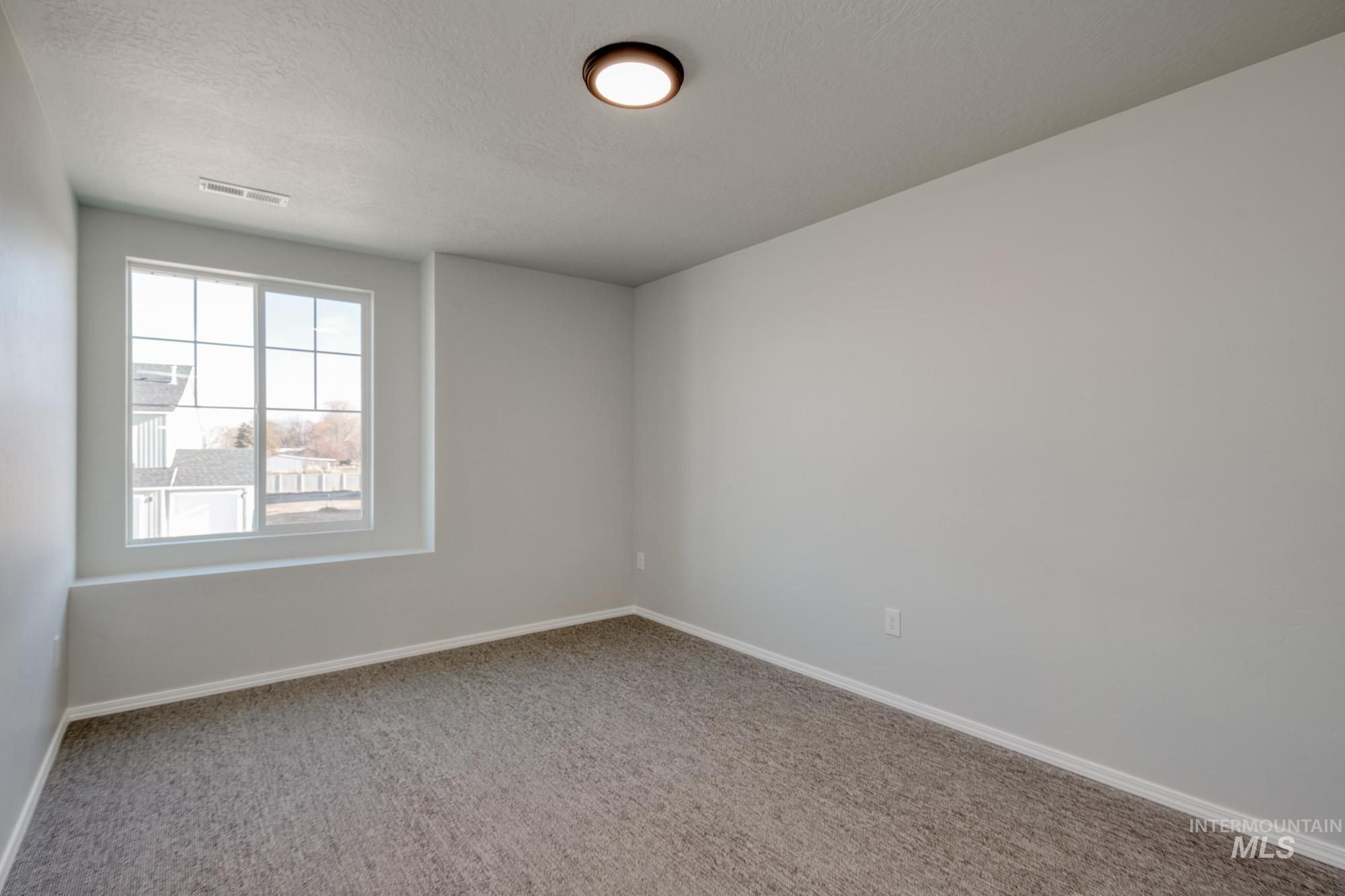 Unfurnished room with light carpet and a textured ceiling