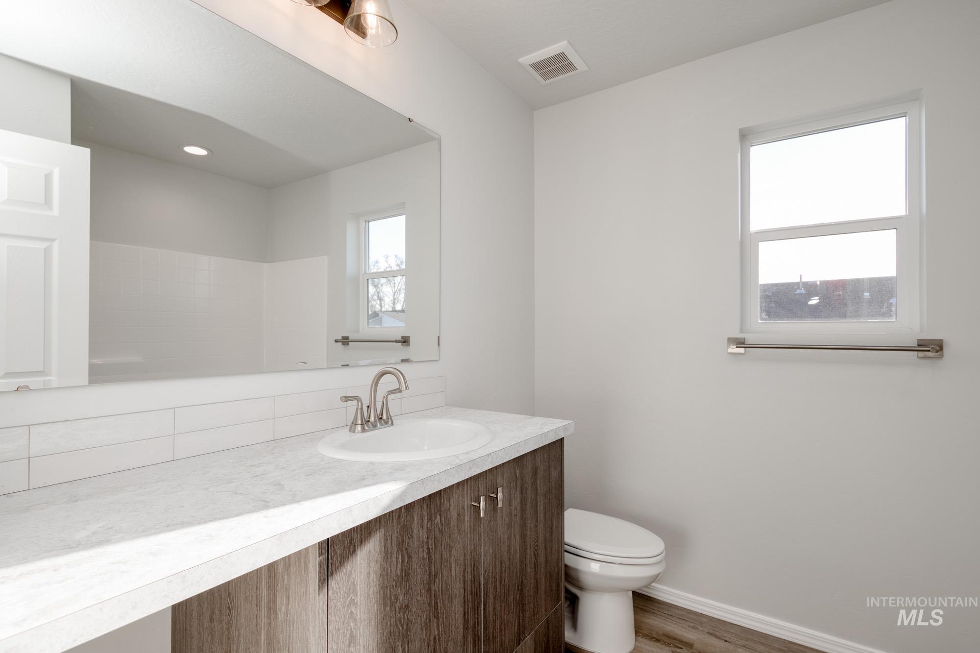 Bathroom with vanity, wood finished floors, and tasteful backsplash