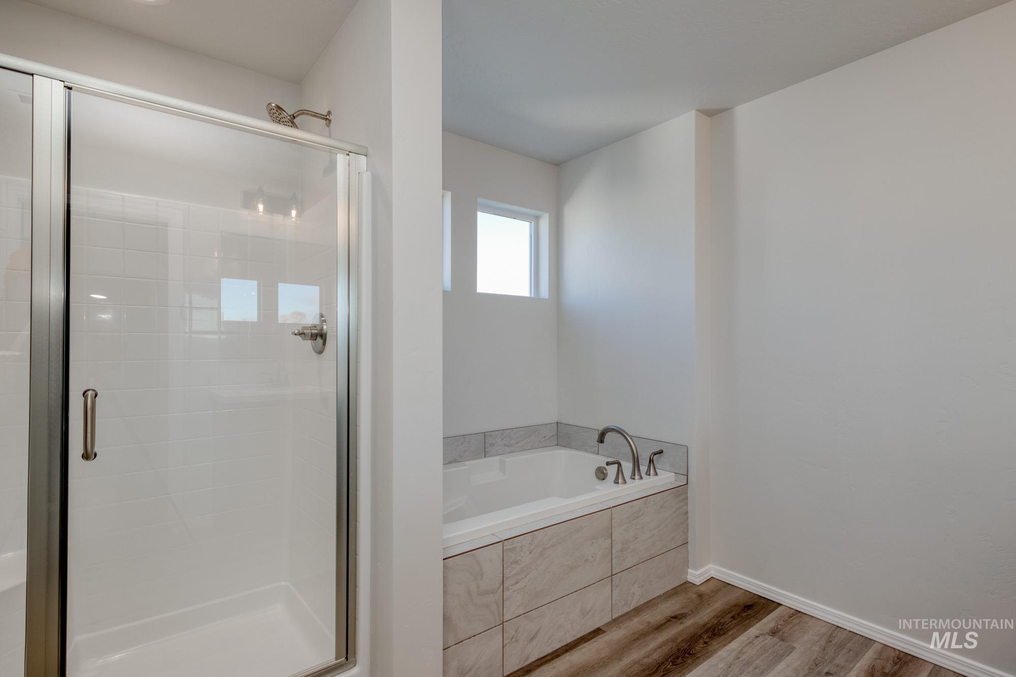 Bathroom with a garden tub, a shower stall, and wood finished floors