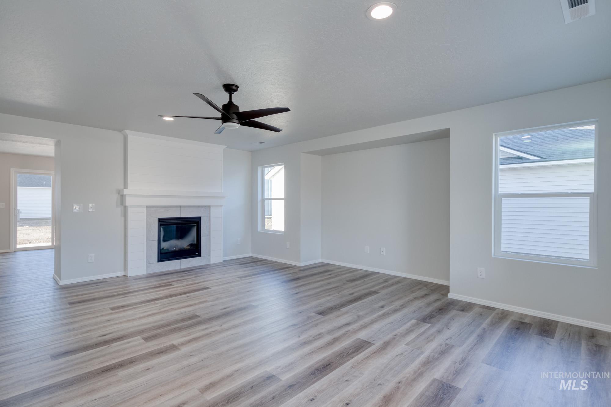 Unfurnished living room featuring a fireplace, a ceiling fan, light wood finished floors, and recessed lighting