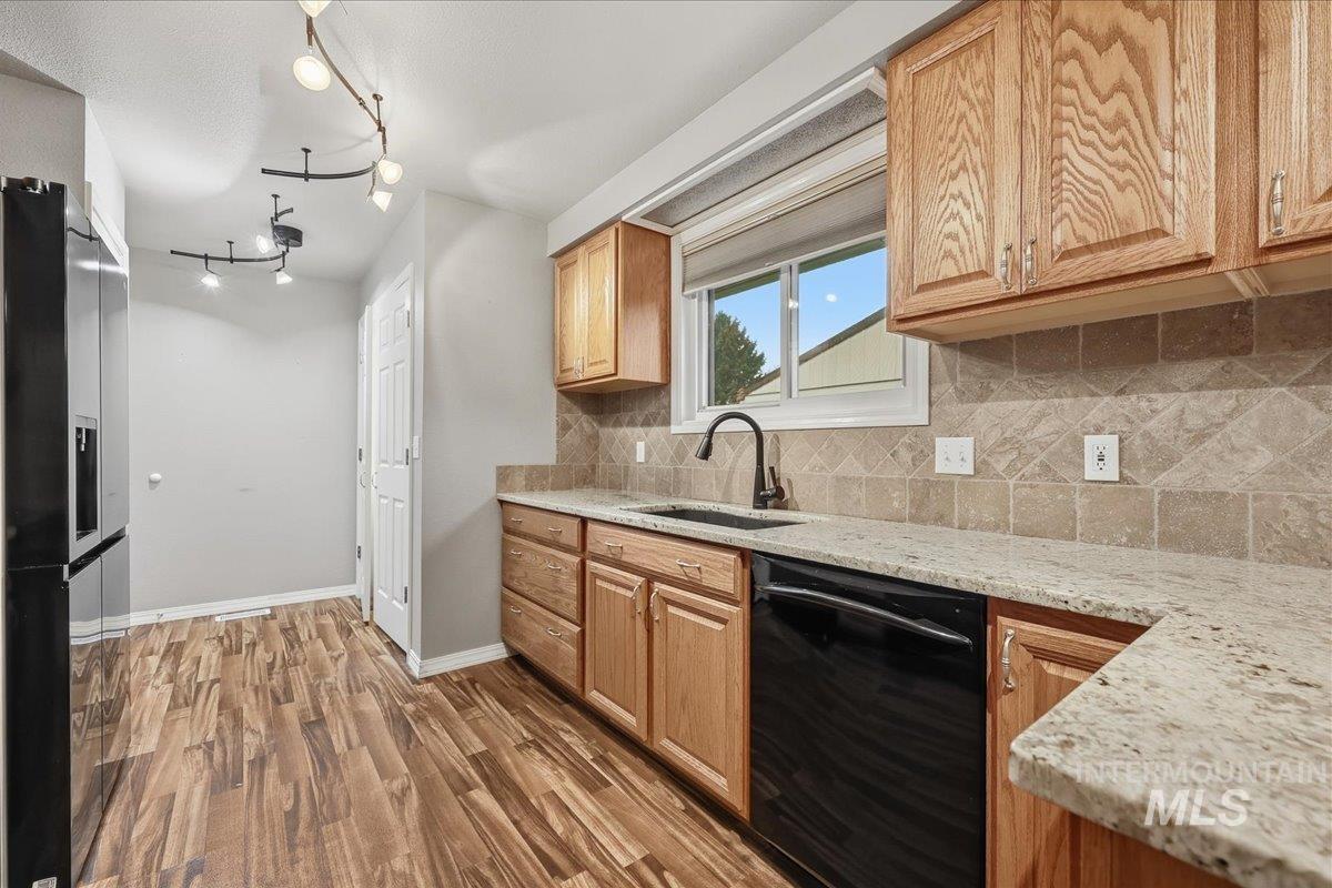 Kitchen featuring dishwasher, high end fridge, light stone counters, dark wood finished floors, and decorative backsplash