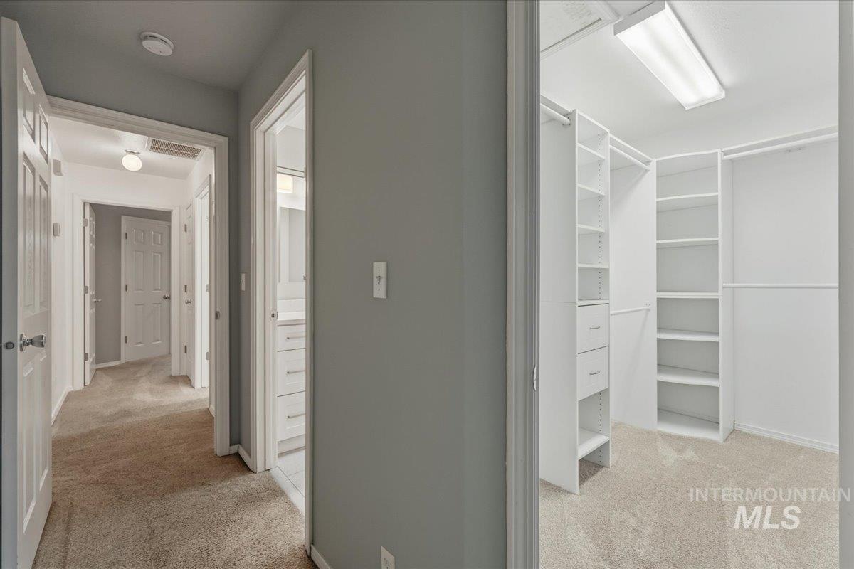 Corridor with light colored carpet and baseboards