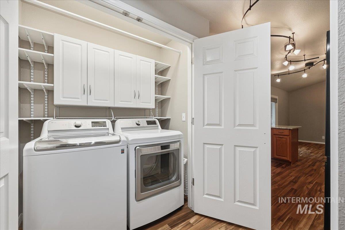 Laundry area with separate washer and dryer, dark wood-type flooring, cabinet space, and a textured ceiling
