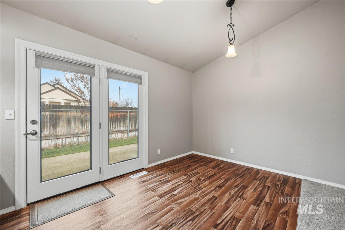Spare room featuring wood finished floors and vaulted ceiling