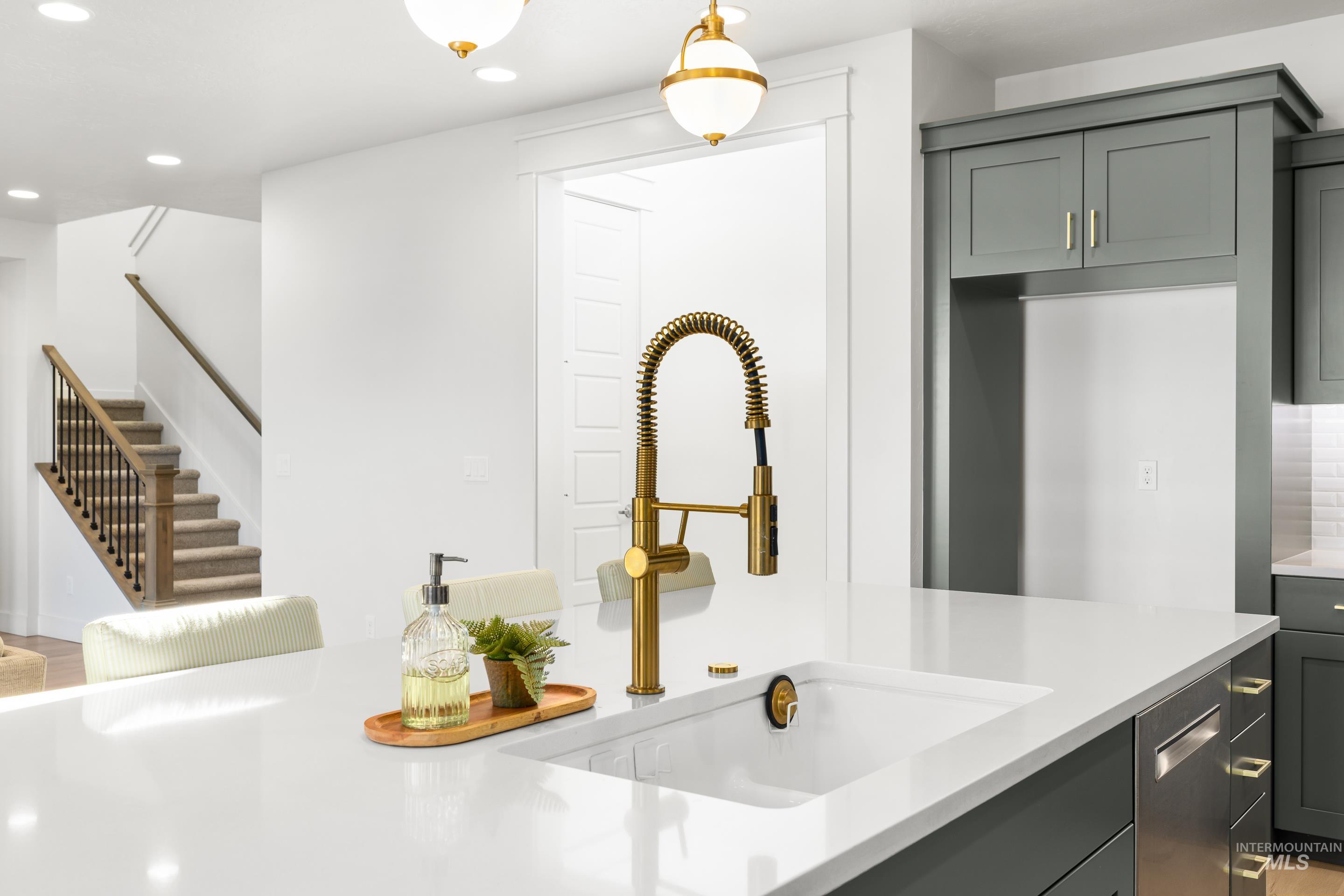 Kitchen with recessed lighting, decorative light fixtures, light stone counters, and gray cabinetry