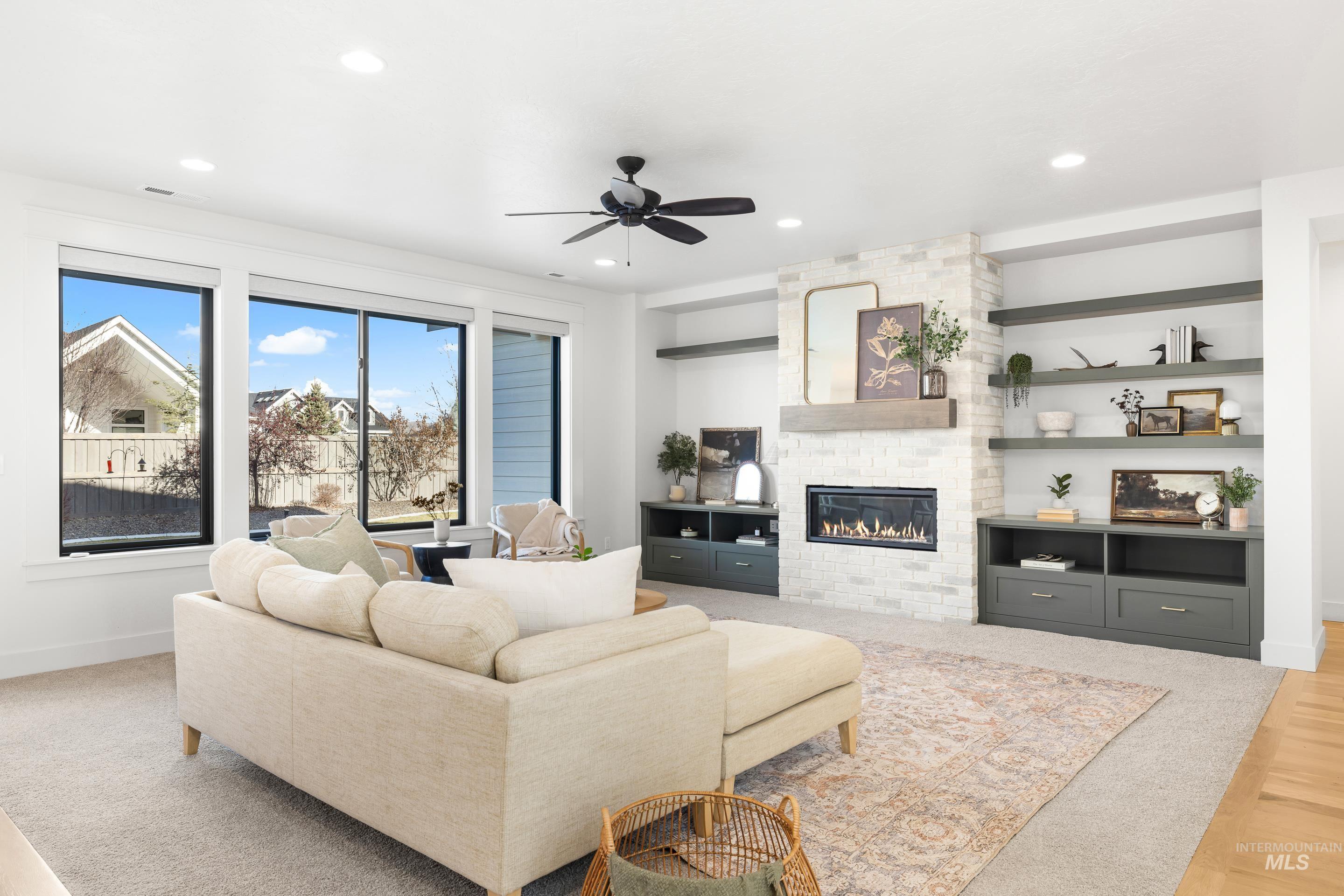 Living room featuring a fireplace, a ceiling fan, recessed lighting, light wood-style floors, and built in shelves