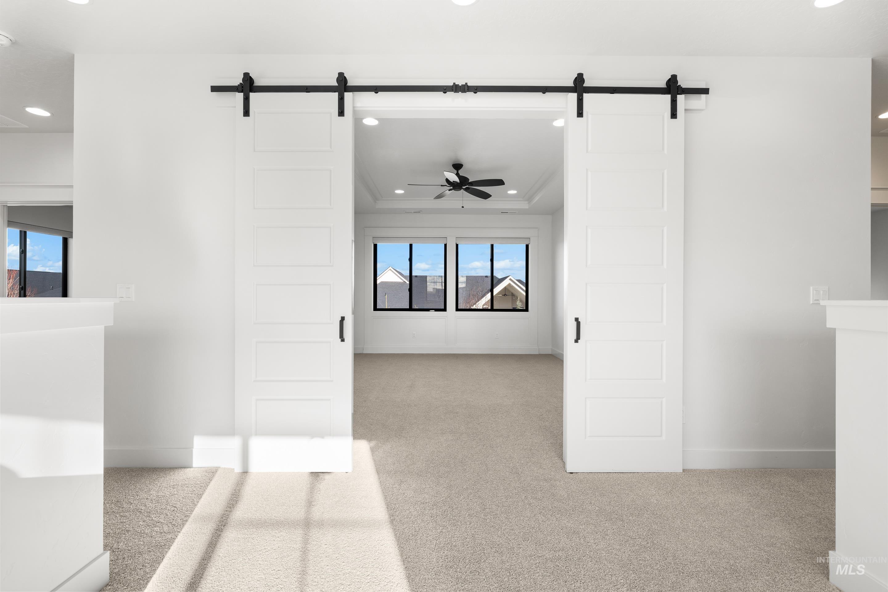 Hall featuring a barn door, recessed lighting, and light colored carpet