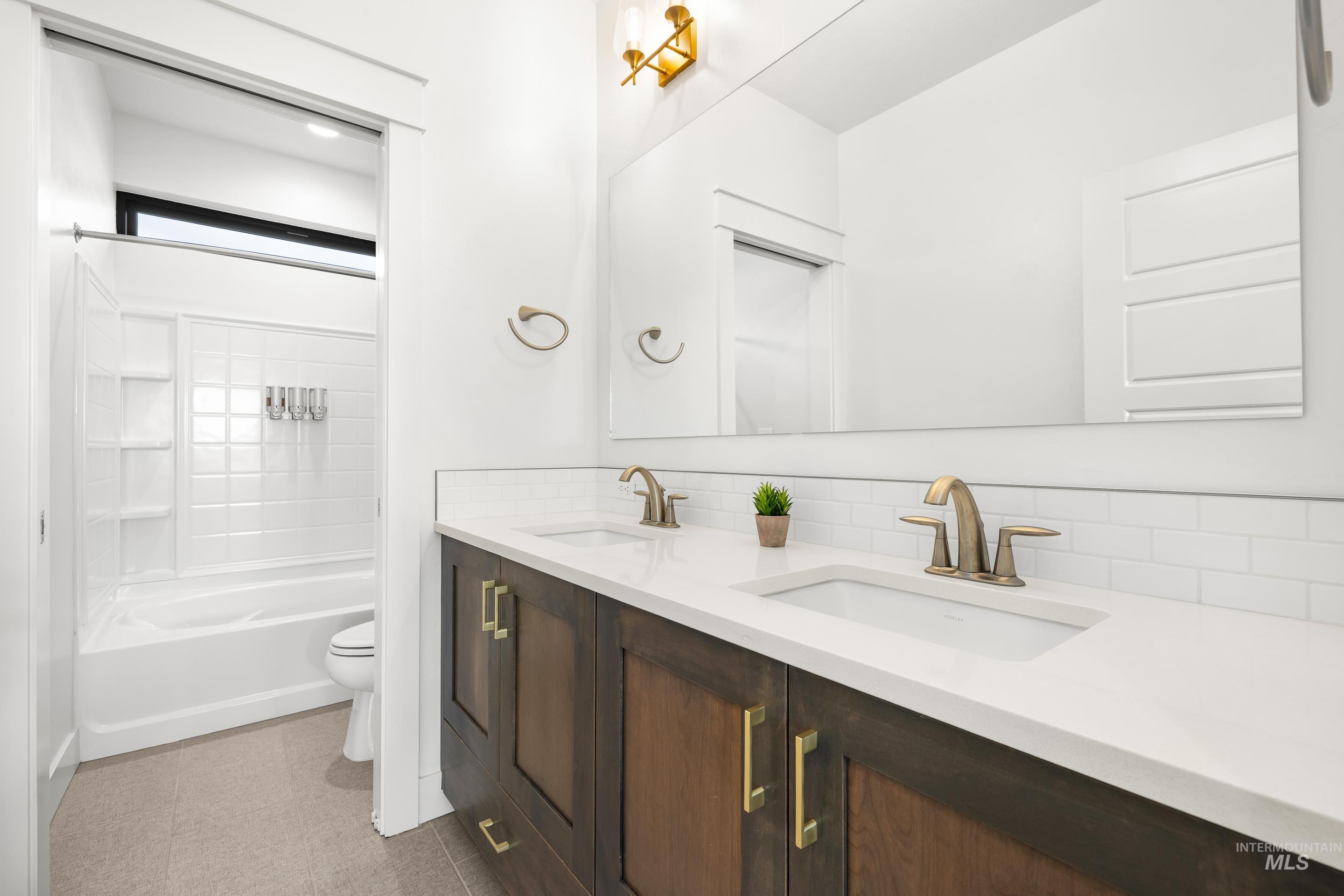 Full bathroom featuring double vanity, backsplash, and shower / bathtub combination