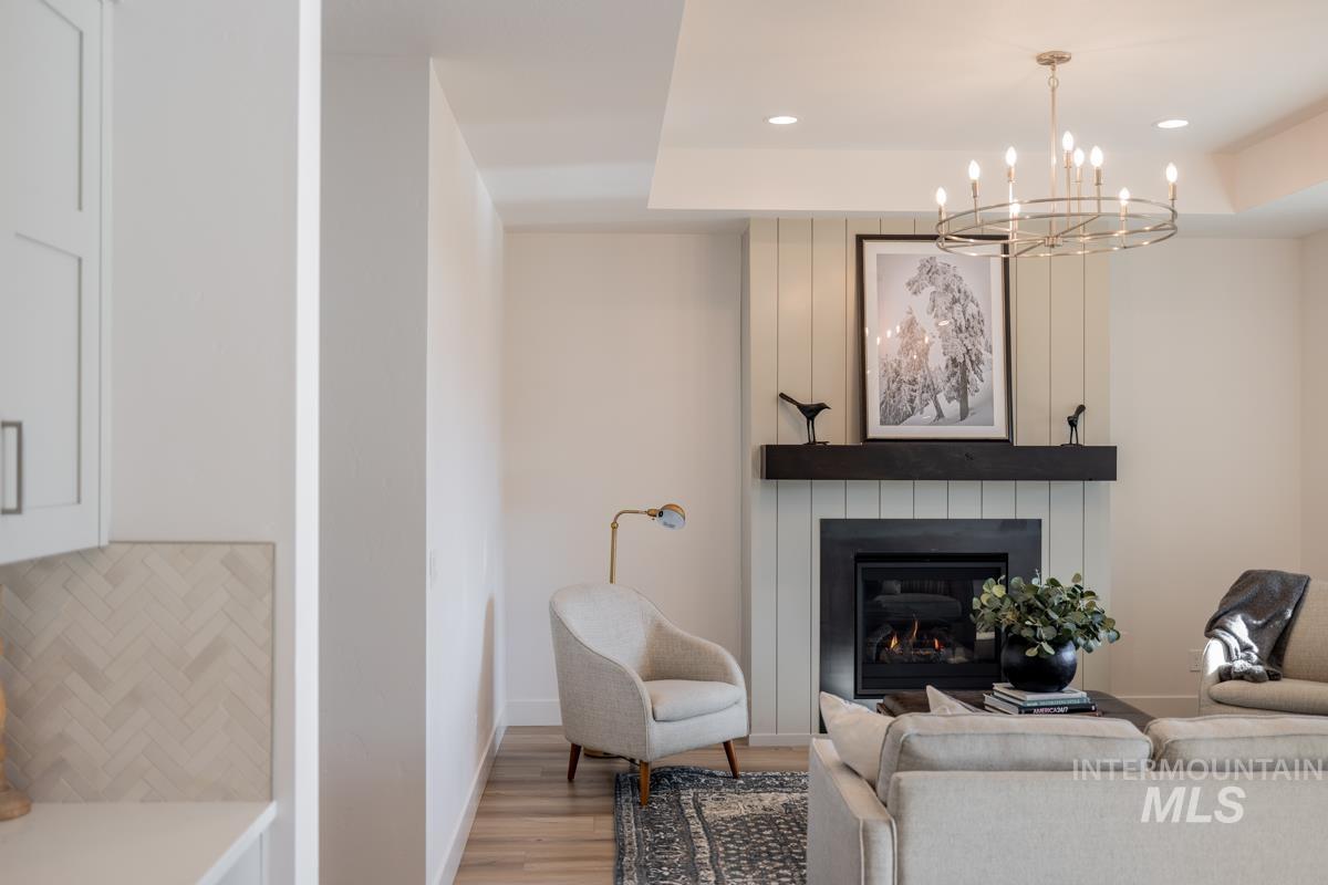 Living room featuring wood finished floors, a fireplace, recessed lighting, a chandelier, and a tray ceiling