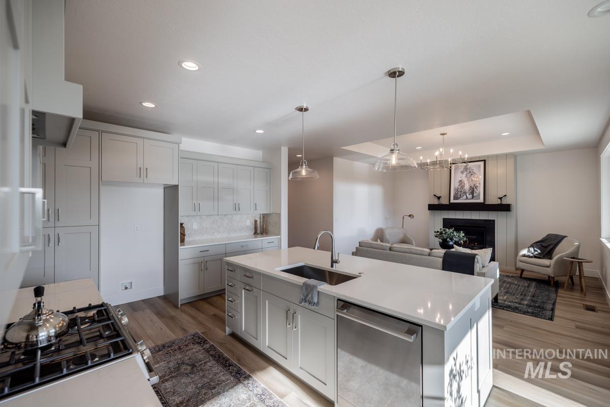 Kitchen featuring decorative backsplash, appliances with stainless steel finishes, hanging light fixtures, a large fireplace, and open floor plan